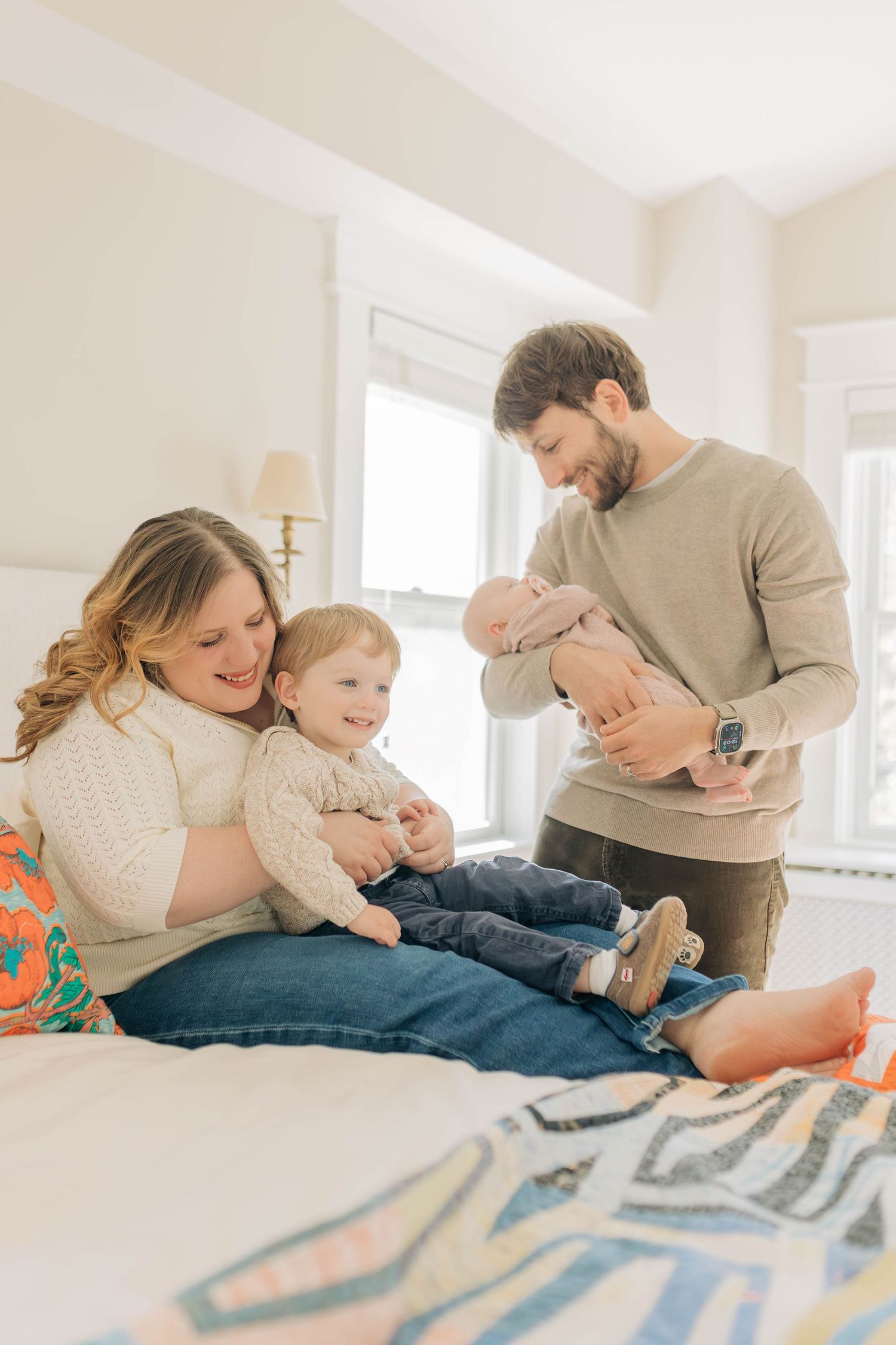 Intimate family cuddle session on a geometric patterned blanket in natural light.