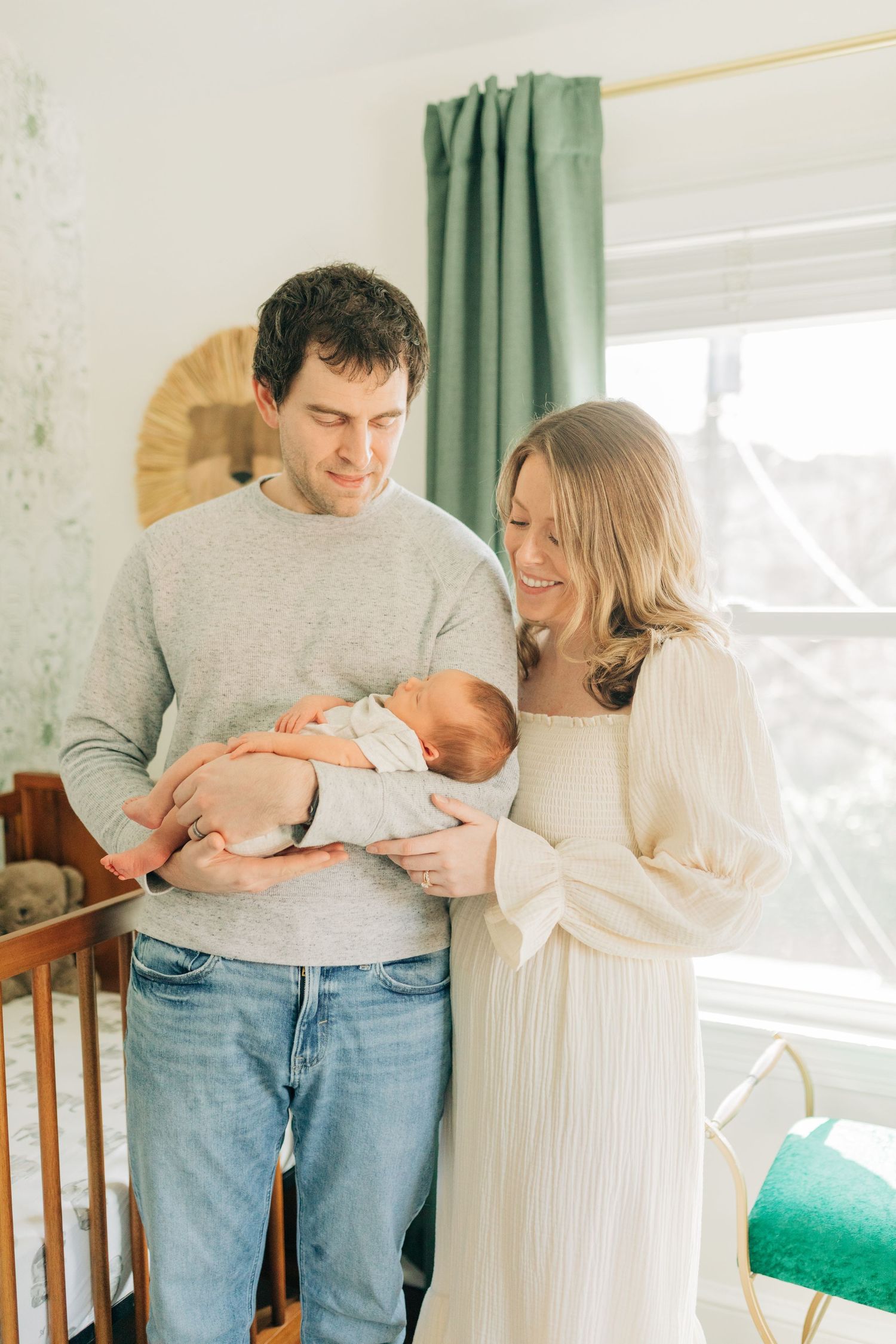 Tender family moment with newborn in nursery decorated with wooden furniture.