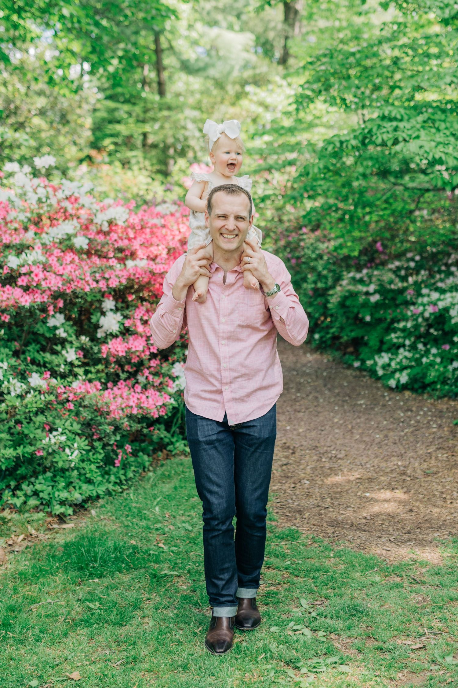 Walking along a garden path with blooming azaleas and green foliage in the background.