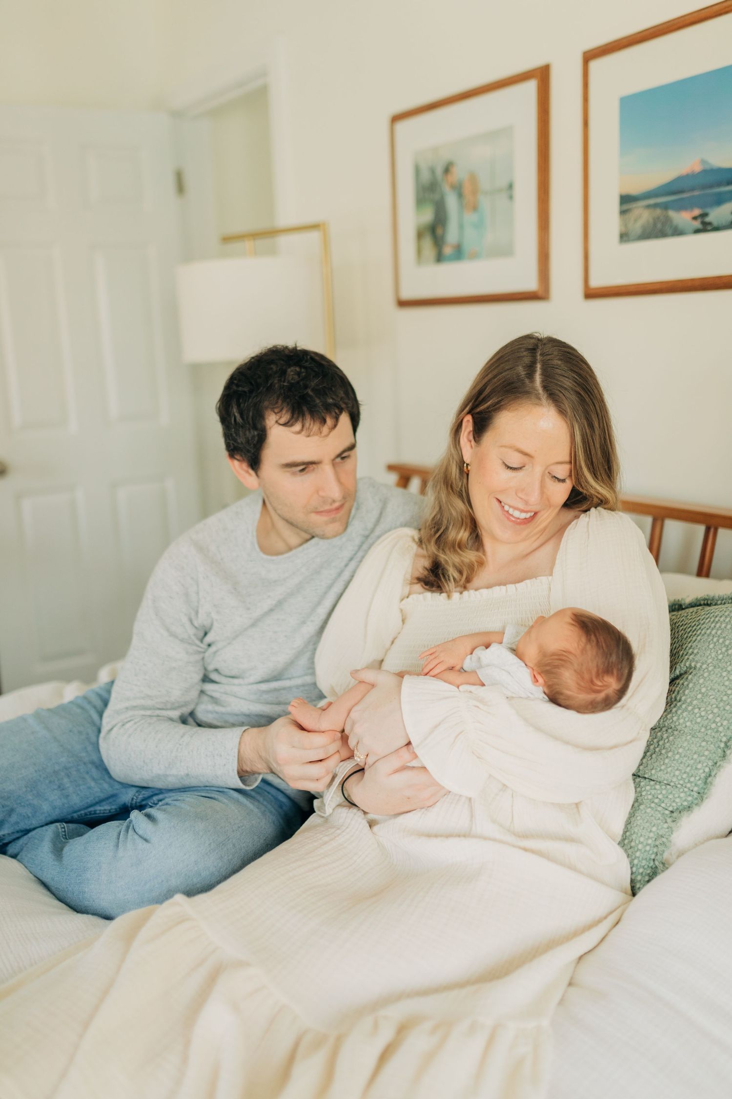 Tender family moment captured on white bedding with soft natural lighting.