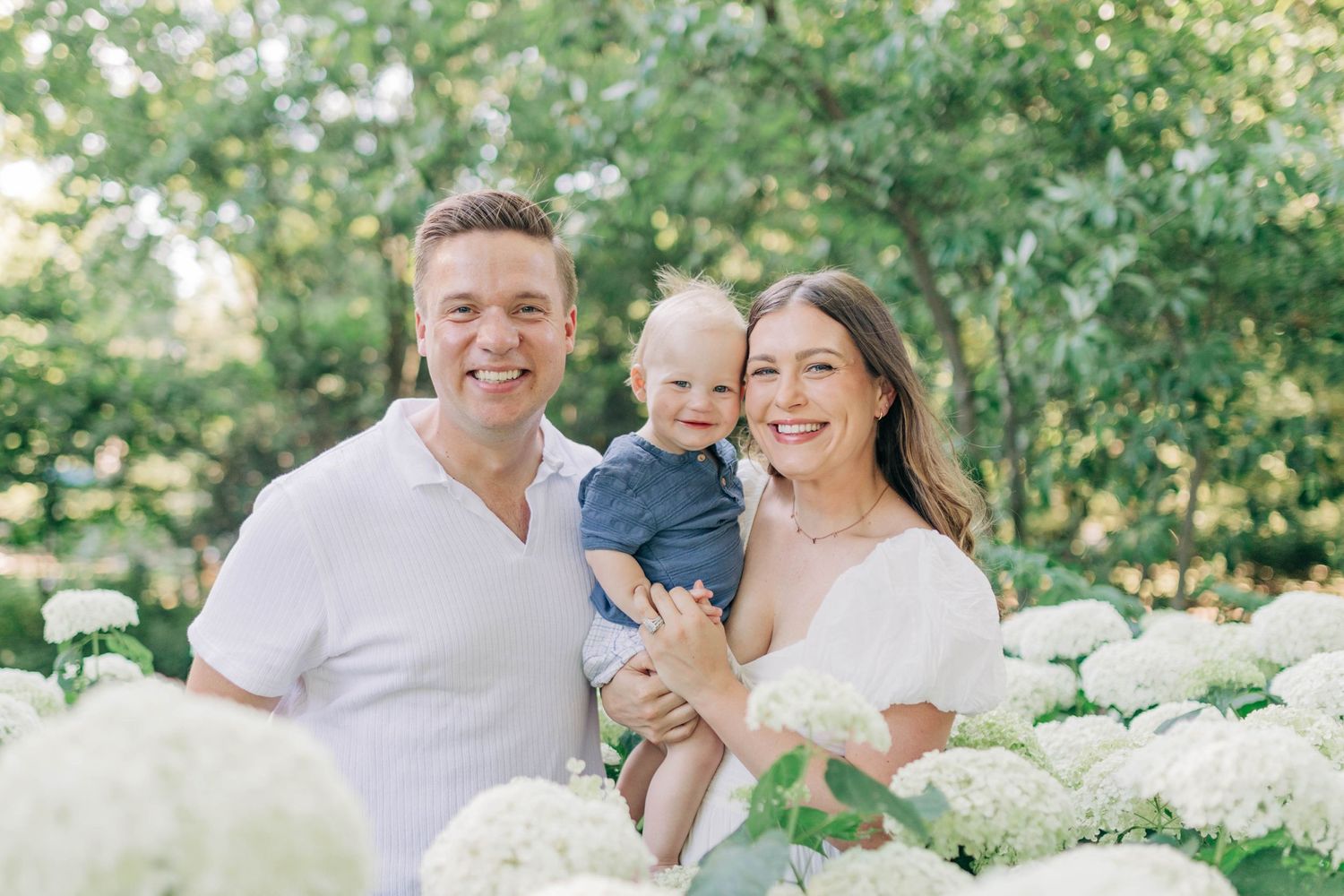 Candid family moments captured in a garden setting with white flowers.