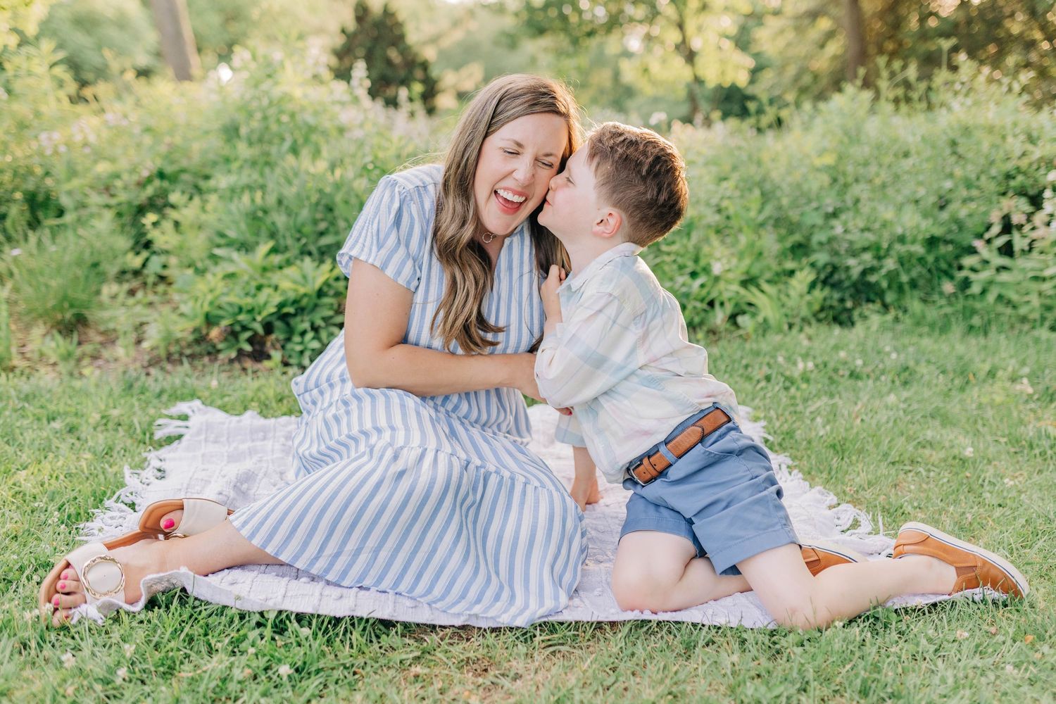 Candid moments shared during a relaxed family photo session in a green outdoor setting.