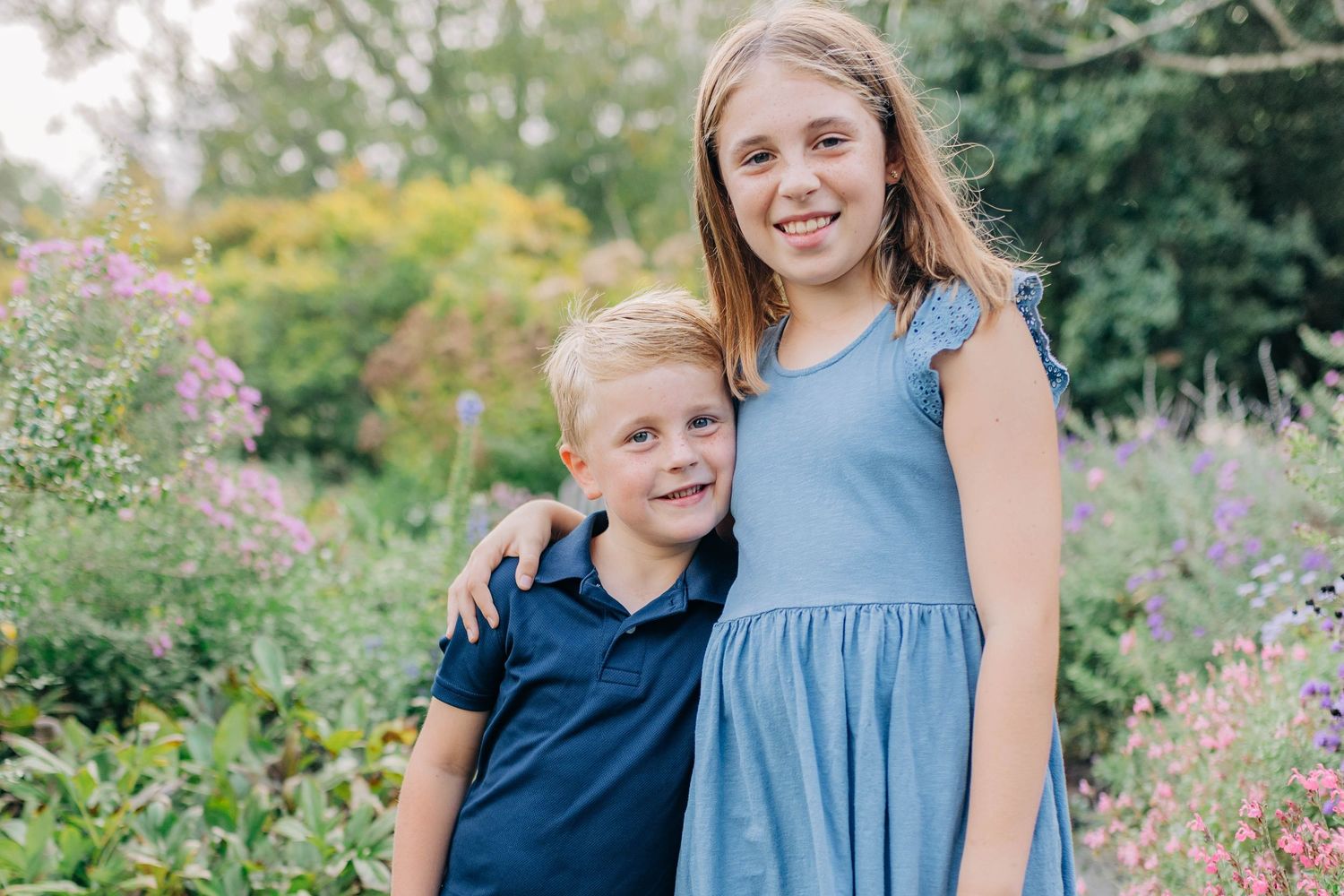 Outdoor family photography session among blooming garden flowers.