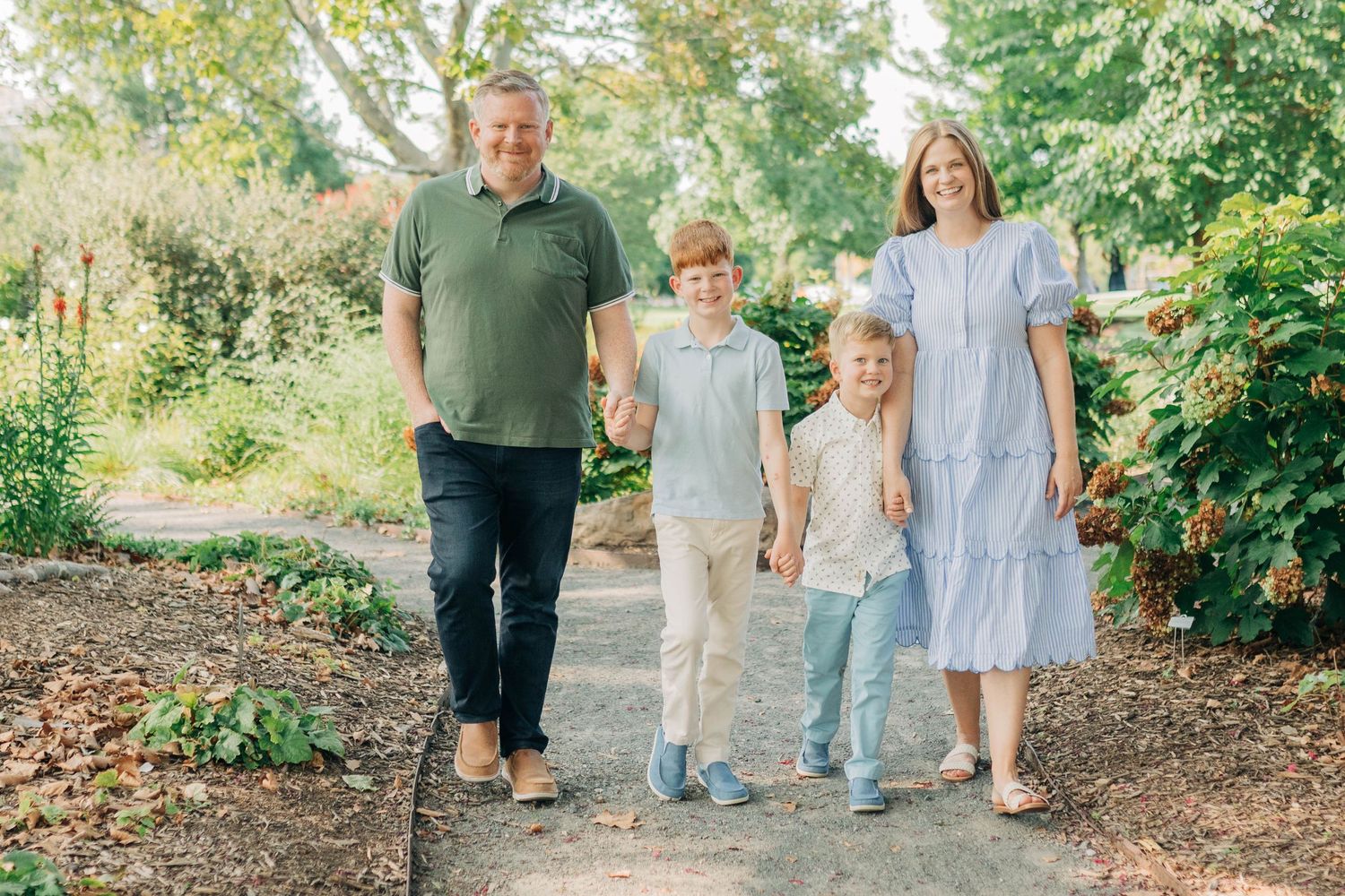 Natural light family photography session in a landscaped garden with blooming flowers.