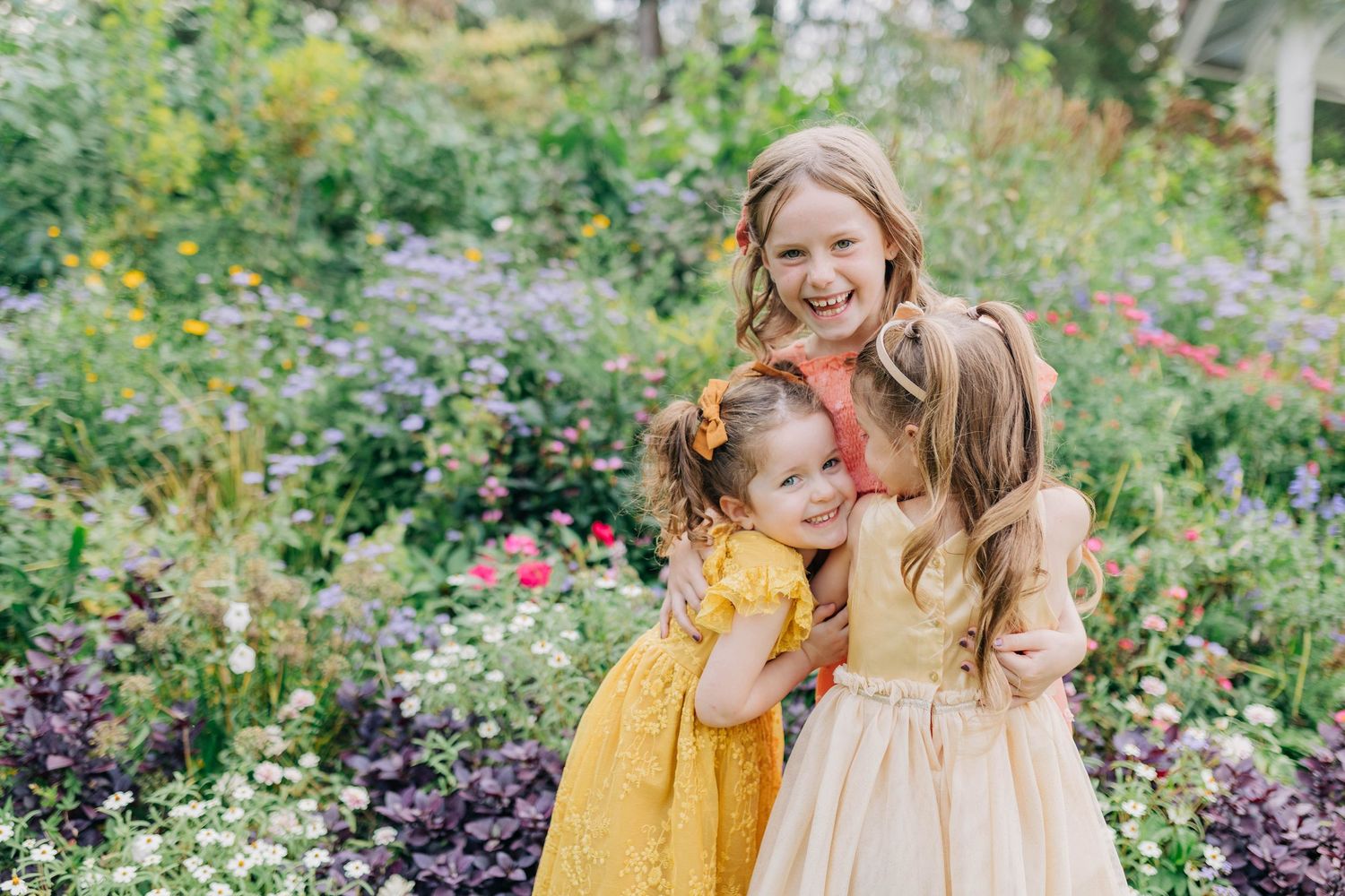 A dreamy garden portrait session with pastel dresses among blooming summer flowers.