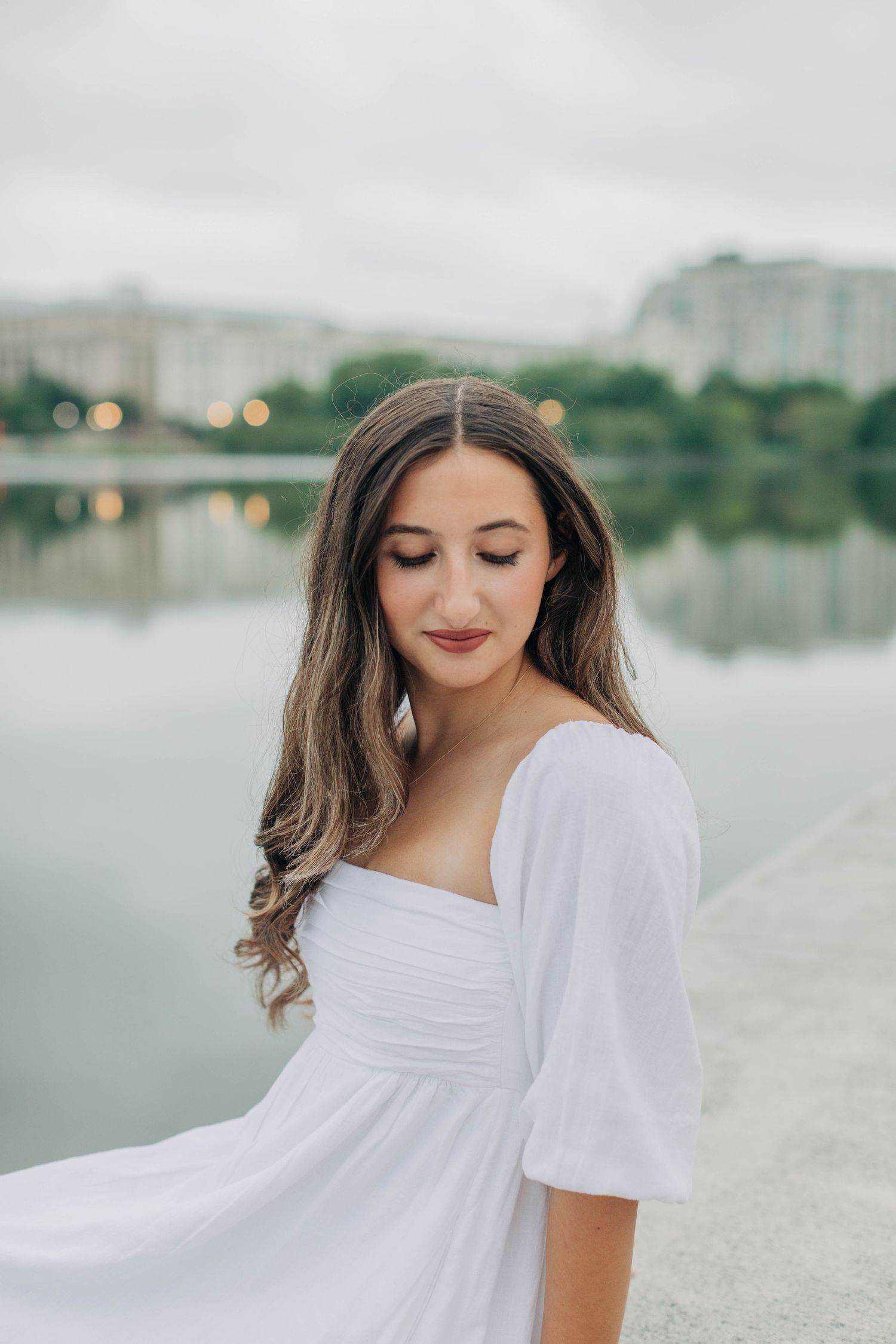 Serene waterfront photoshoot with a misty lake and cityscape in the background.