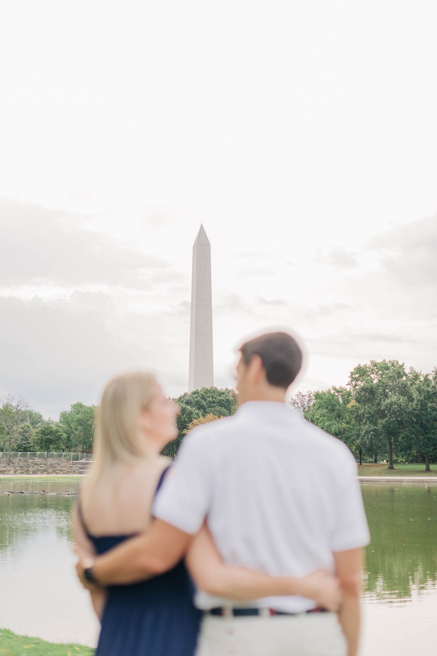 Couple enjoying a romantic moment near the reflecting pool with Washington Monument in view.