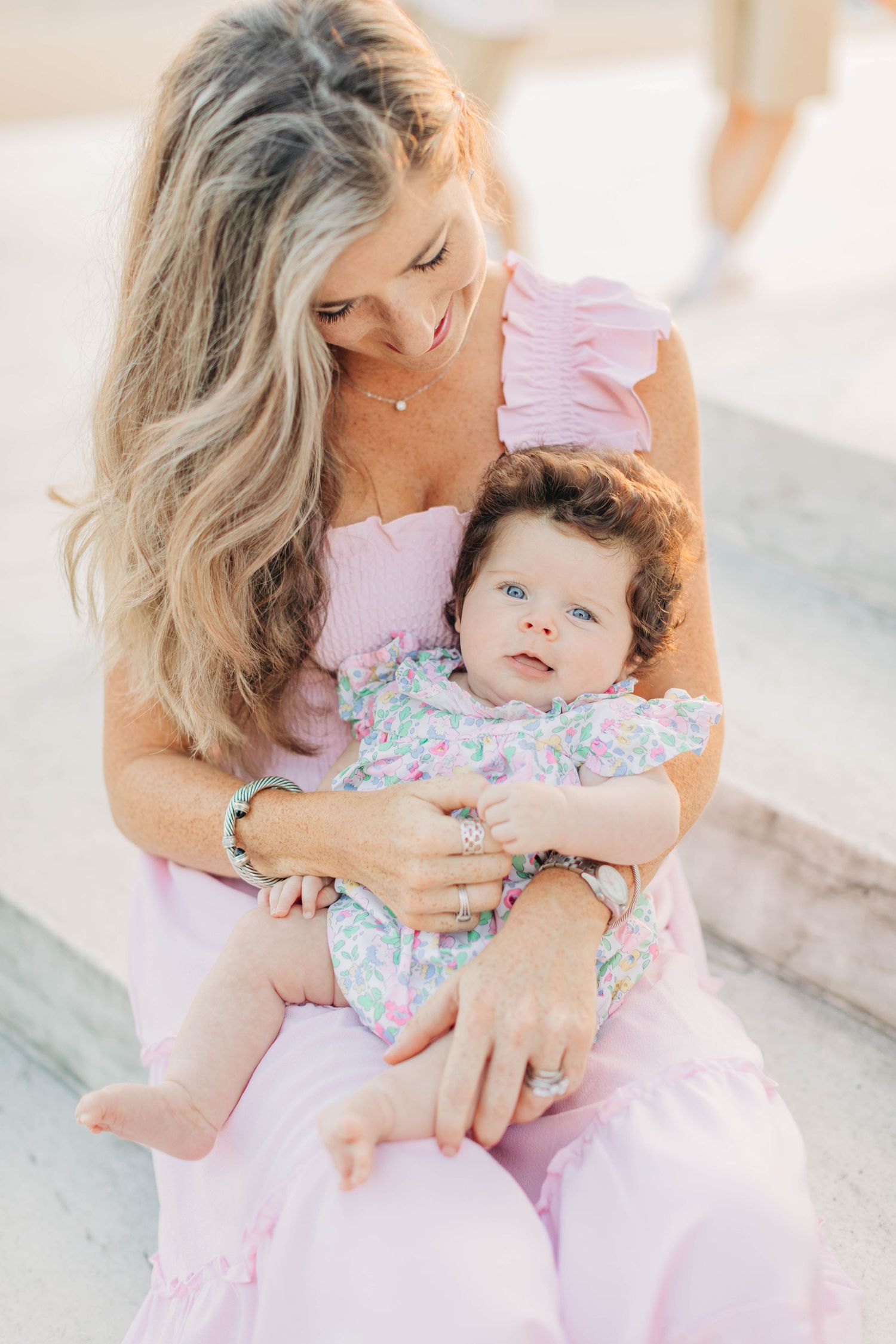 Tender moment between parent and baby during sunset photoshoot.