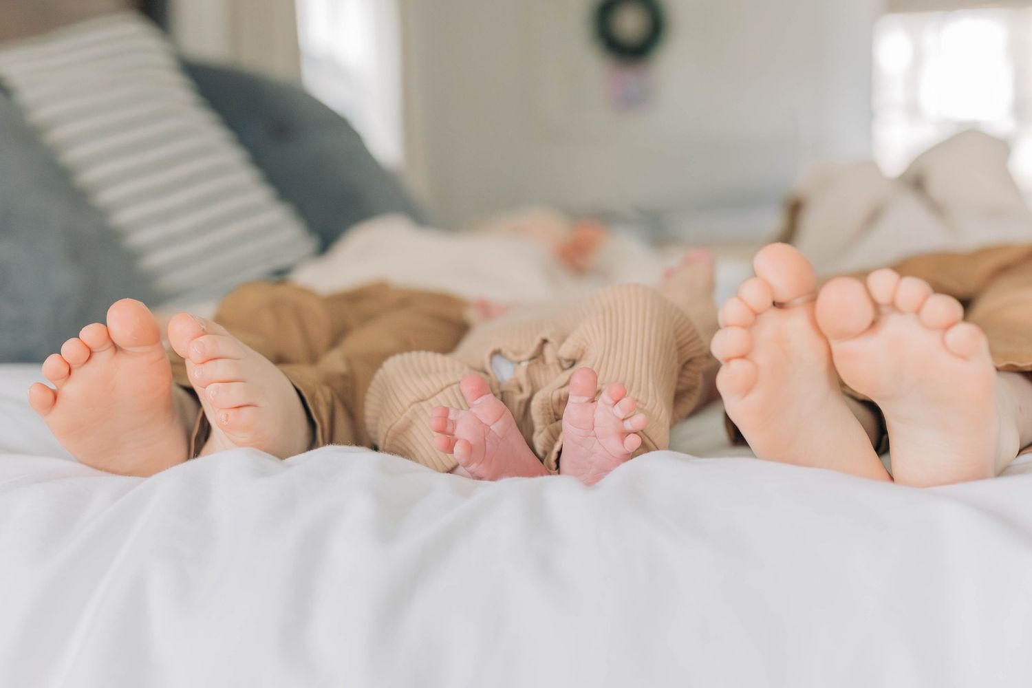 Multiple pairs of newborn baby feet arranged side by side on white fabric.