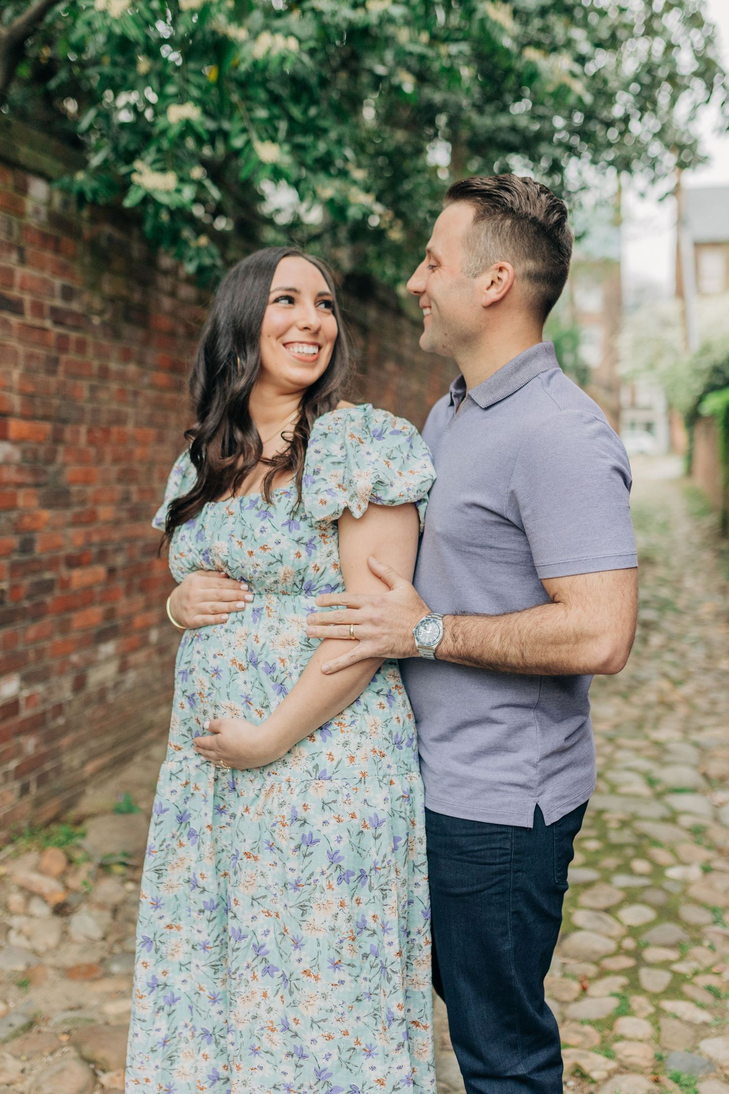 A couple shares an intimate moment on a charming brick-lined cobblestone walkway.