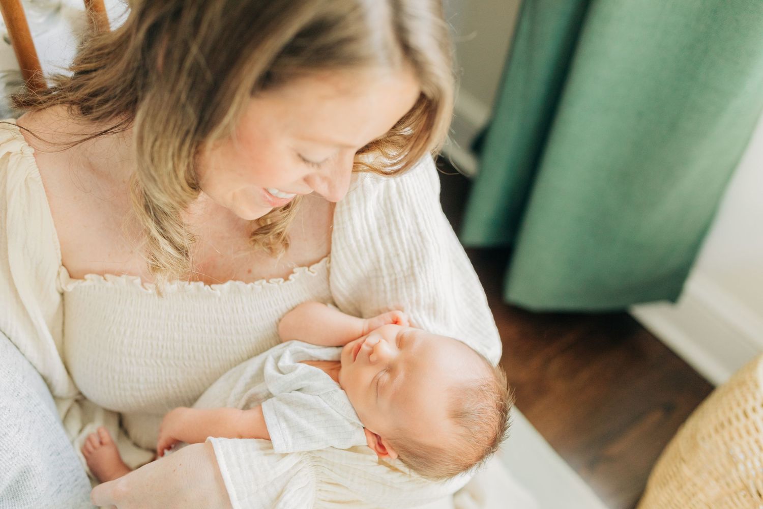 Tender family moment in a bright nursery room with sage green curtains.