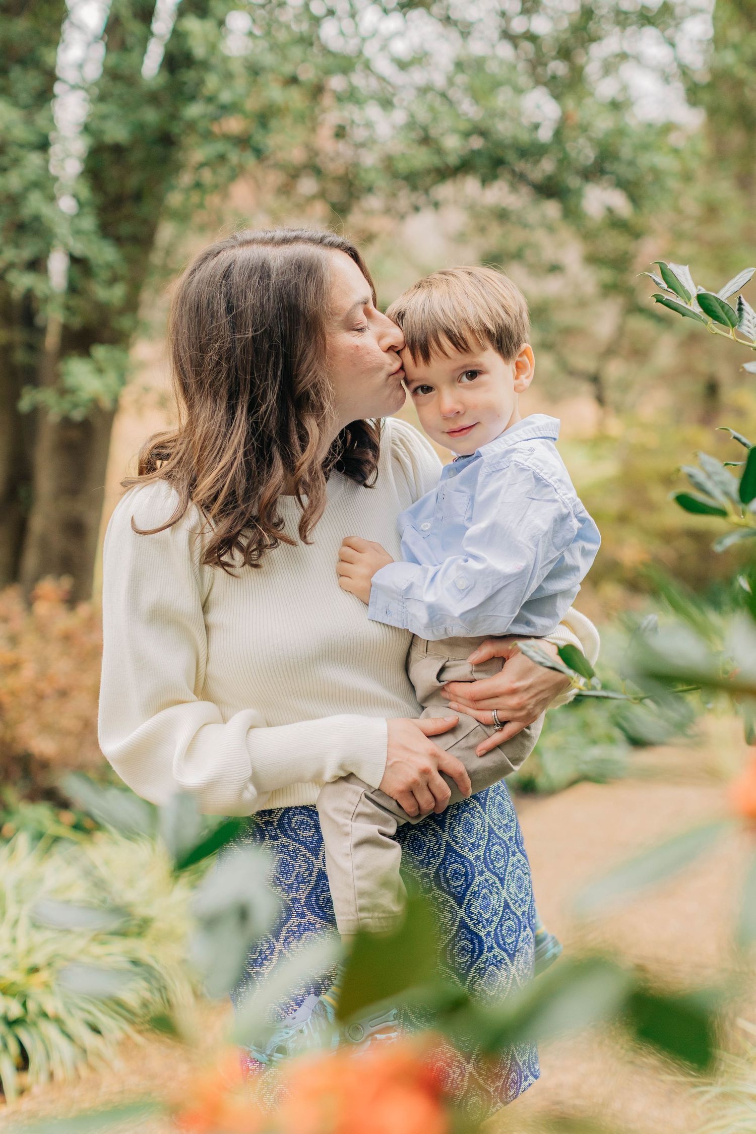 A tender moment captured between parent and child in a garden setting with soft natural lighting.