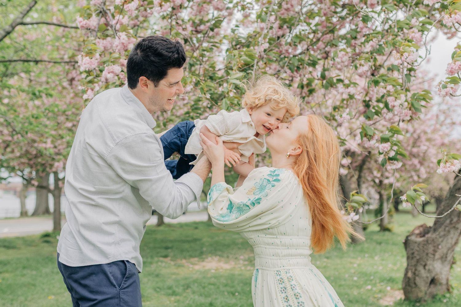 A couple dances together under blooming cherry blossom trees in a spring garden setting.