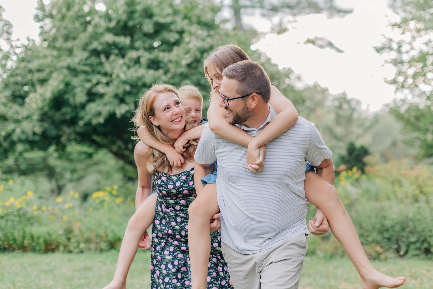 Family members sharing playful moments together against a backdrop of summer foliage.