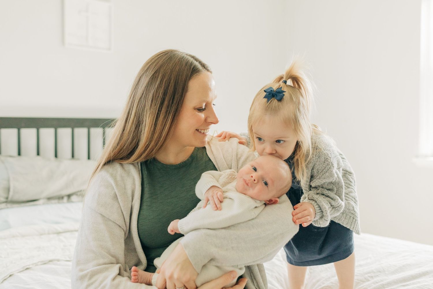 Joyful family moment on bed with toddler and infant sharing cuddles together.