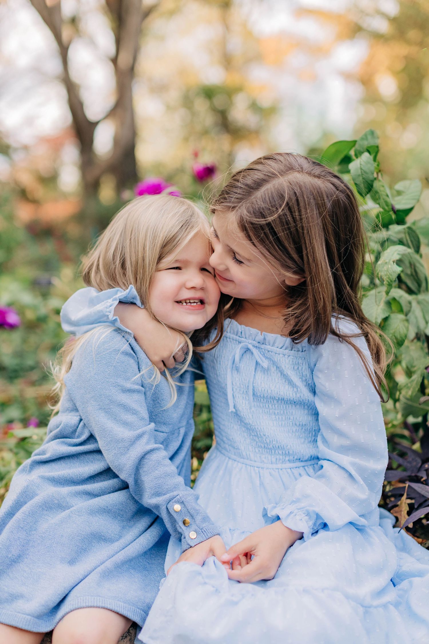Two people in matching blue dresses share sweet moments outdoors.