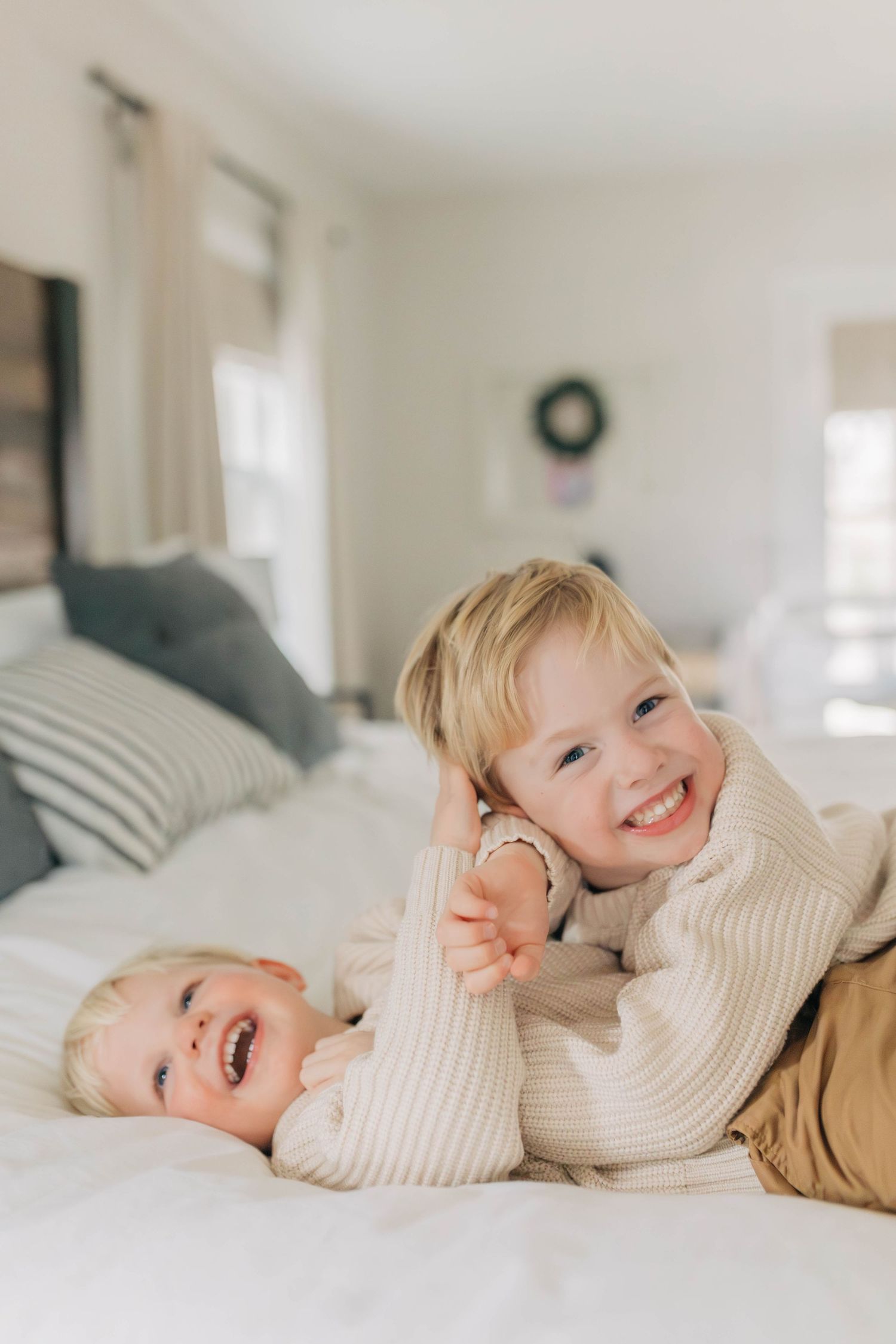 Two children playing and laughing together on a white bed.