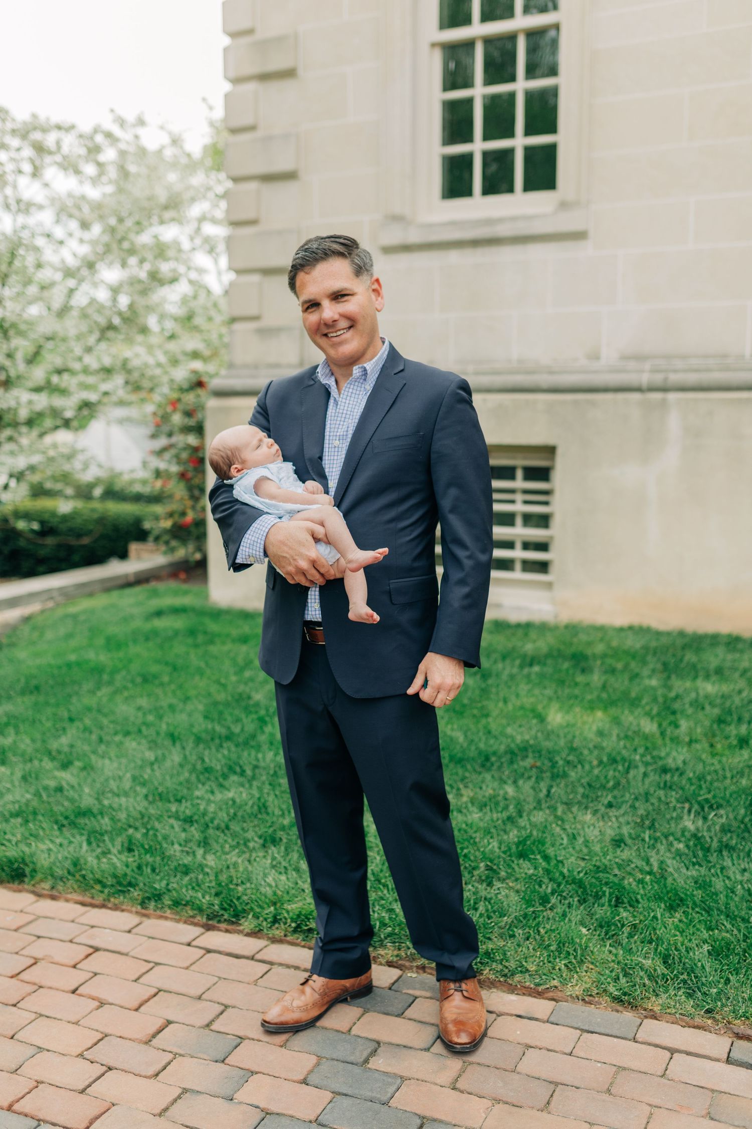 Outdoor family portraits on brick pathway near stone building with windows.