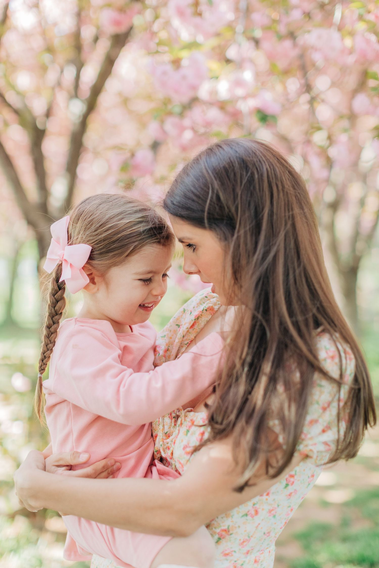 A tender moment between parent and child surrounded by blooming cherry blossoms in spring.