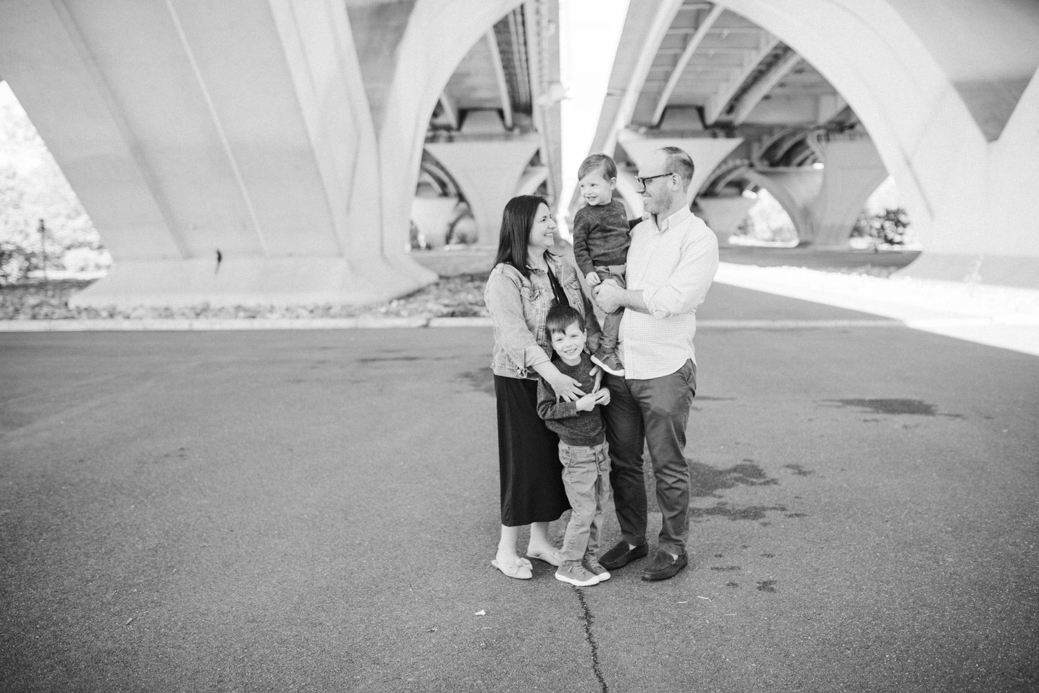Black and white family photo series showing candid moments under architectural elements.