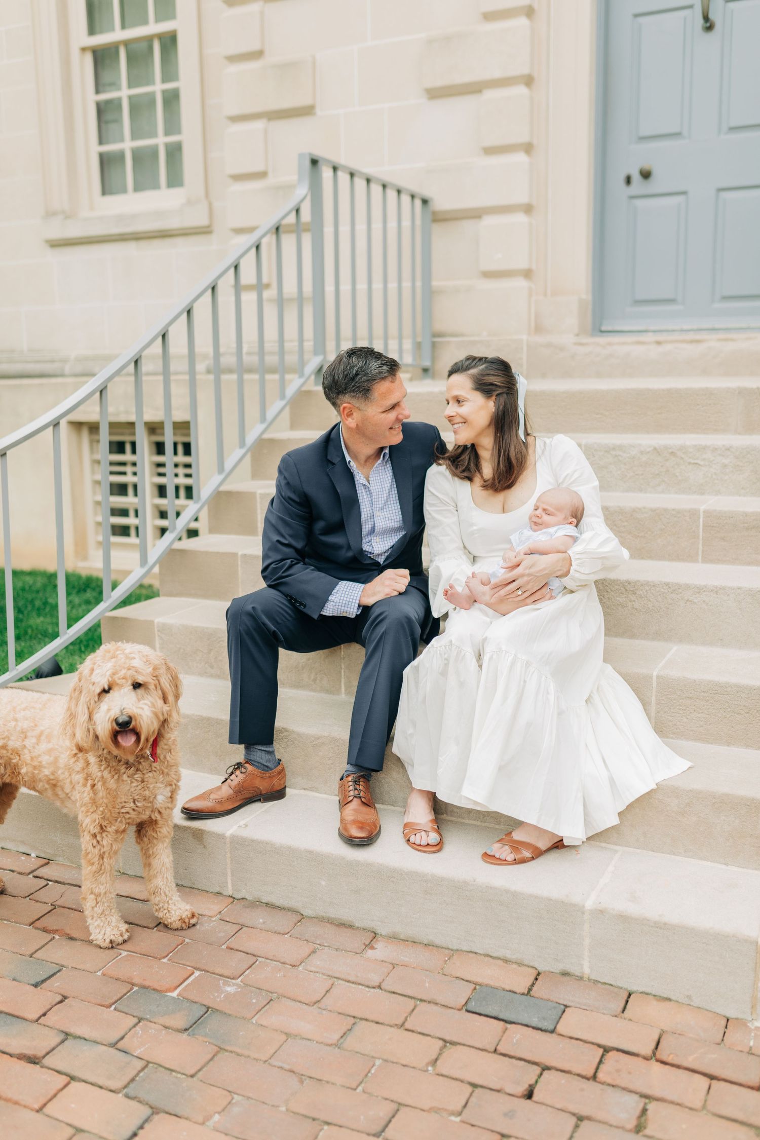 Family portrait with fluffy goldendoodle dog outside classic building with blue door.