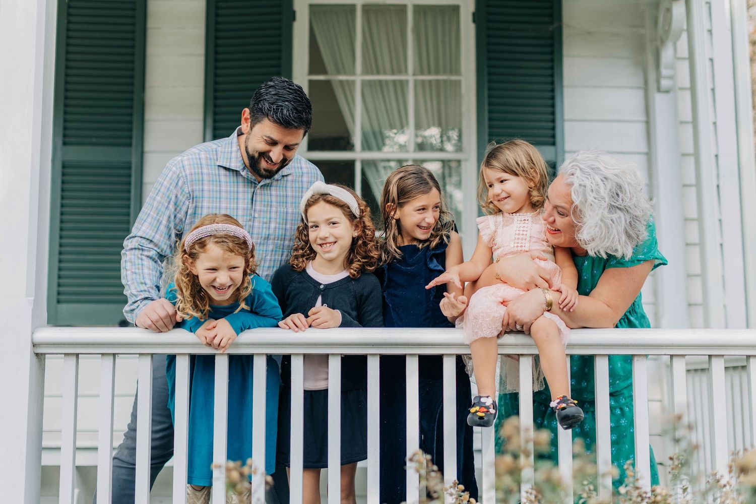 People gathered on white porch steps enjoying outdoor social time together.