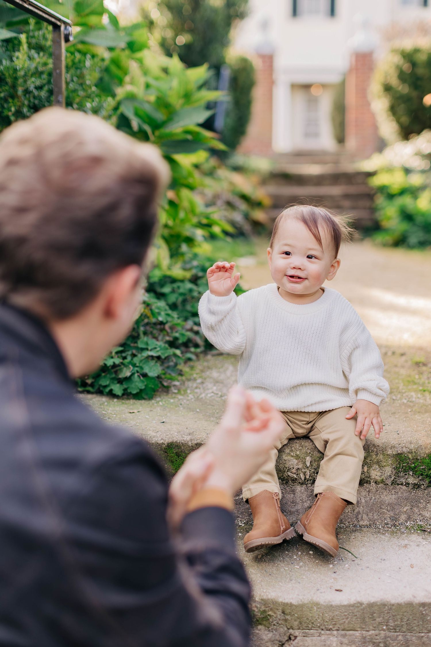 Playful interaction between parent and toddler during outdoor family photoshoot.