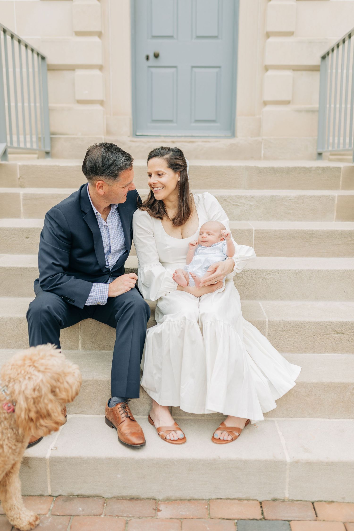 Family with goldendoodle dog sharing tender moment on brick steps.