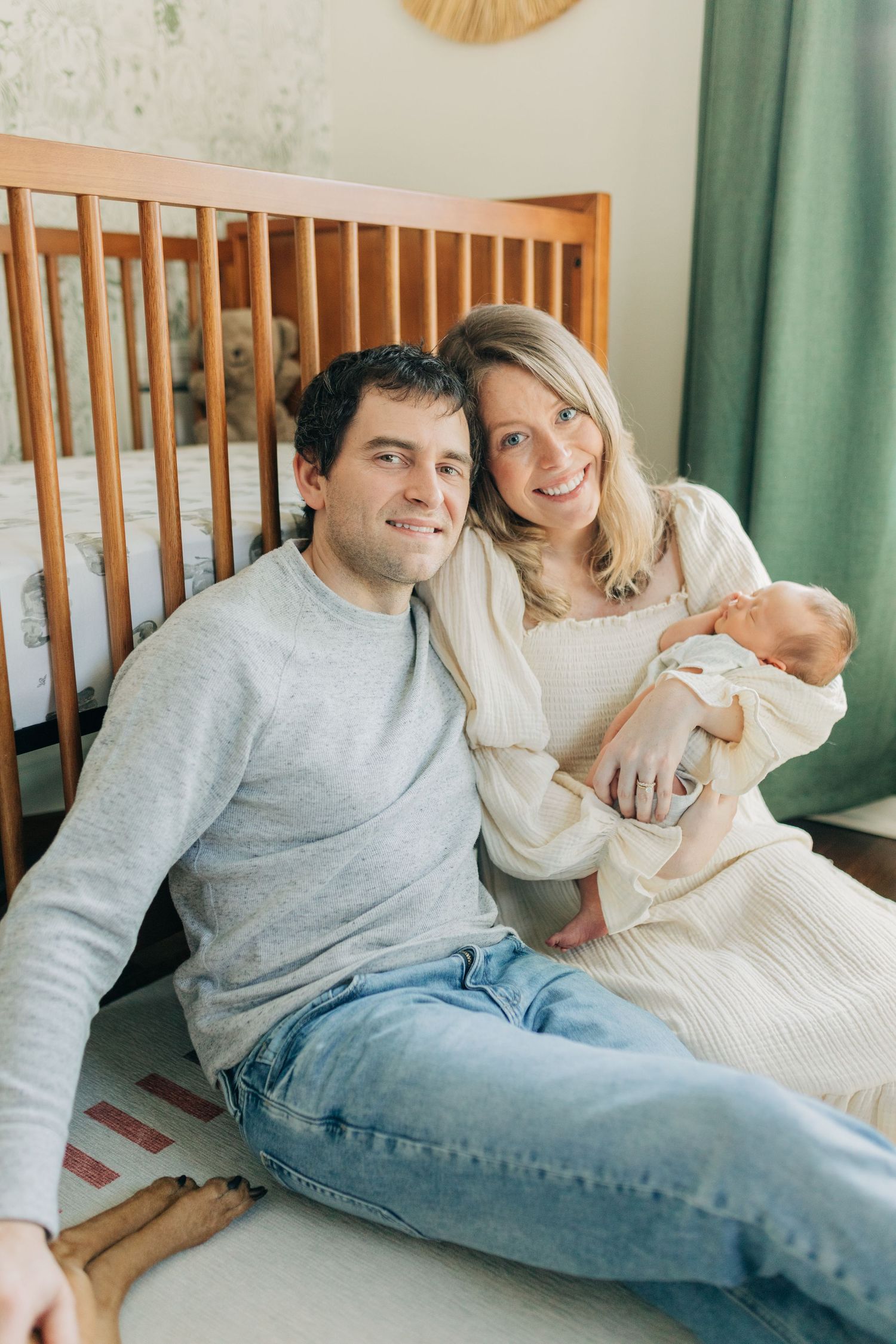 Candid family lifestyle session in nursery with wooden crib and green decor.