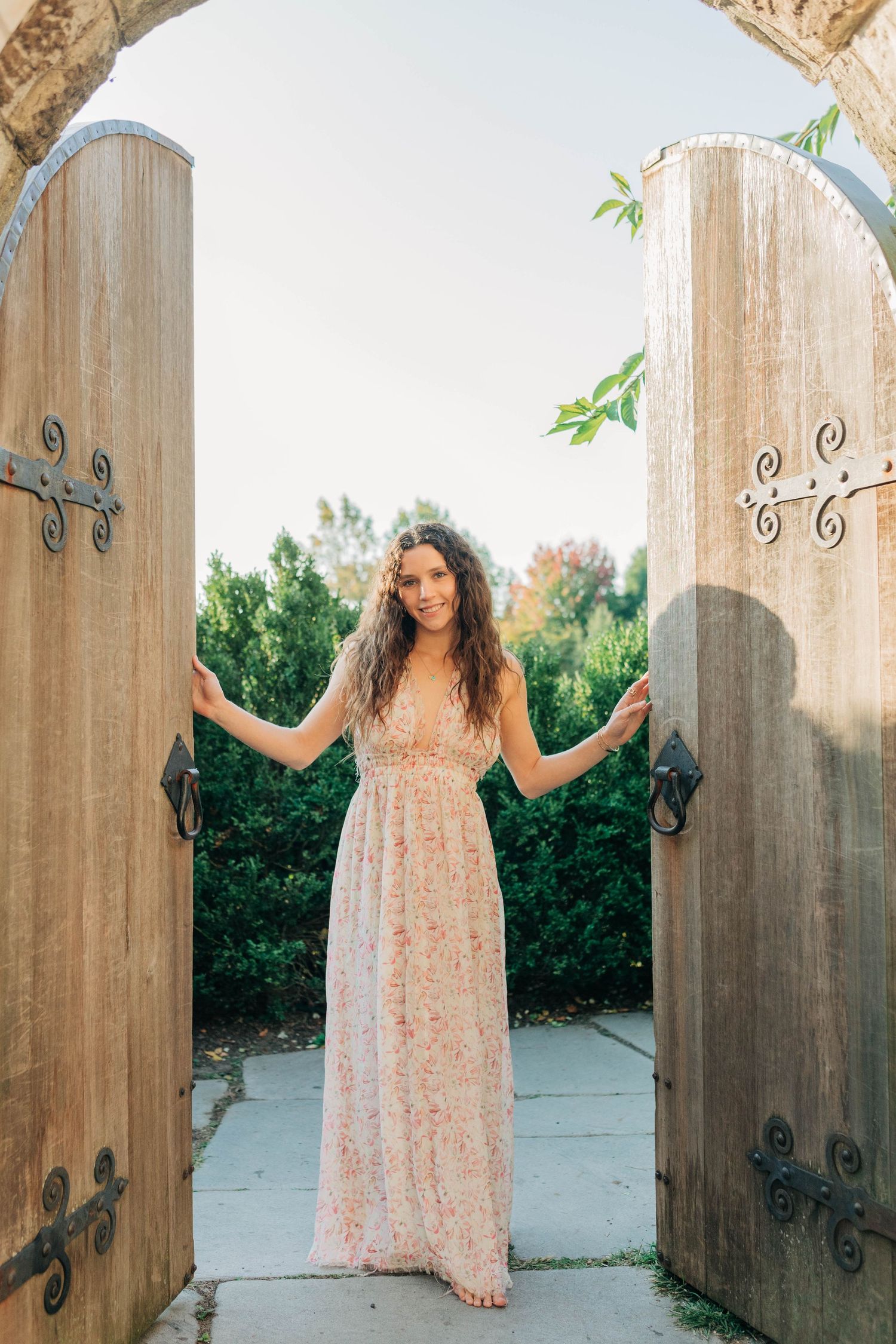 Wooden gates with decorative ironwork frame a series of portrait poses in natural light.