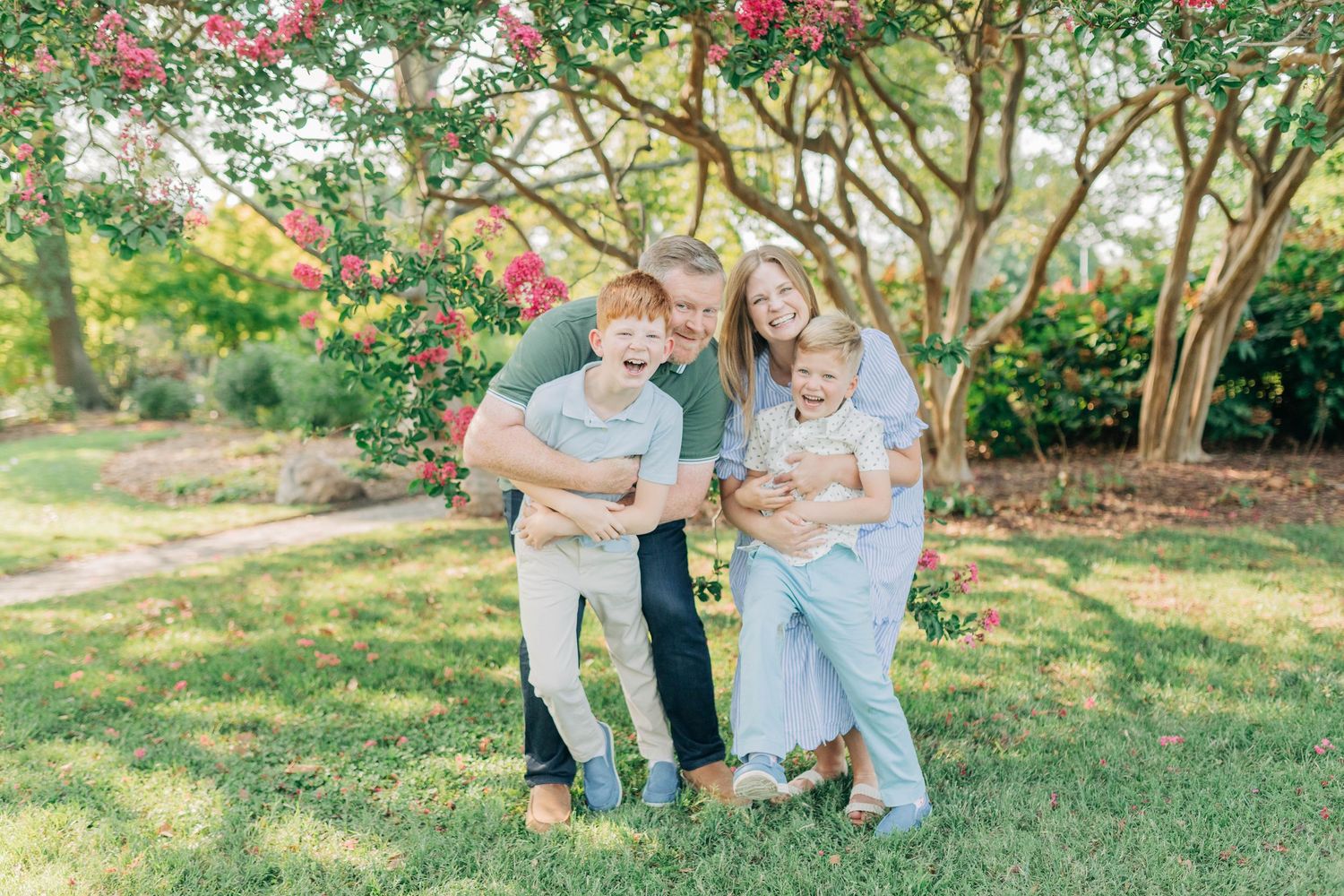 Candid family moments captured in a garden setting with pink flowering trees.