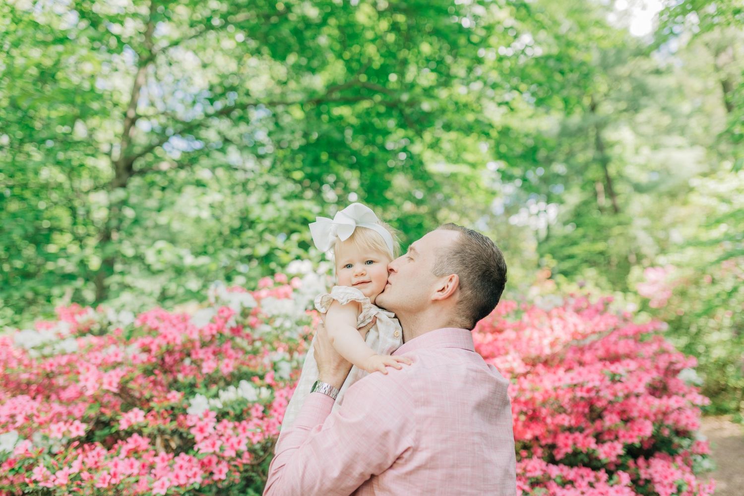 Loving moment captured in a lush garden setting with pink azaleas in bloom.