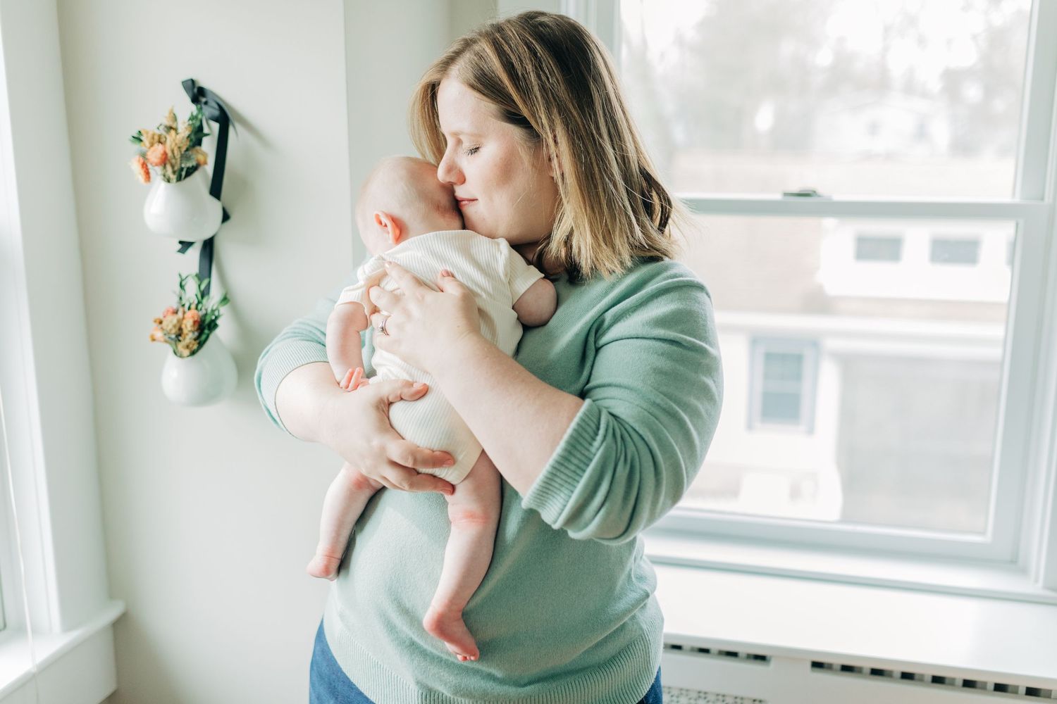 Tender family moments captured in sunlit room with window.