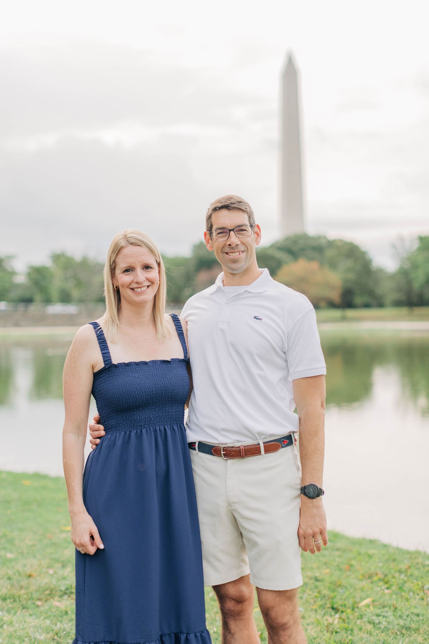 Couple poses for portraits near the Washington Monument and reflecting pool on a cloudy day.