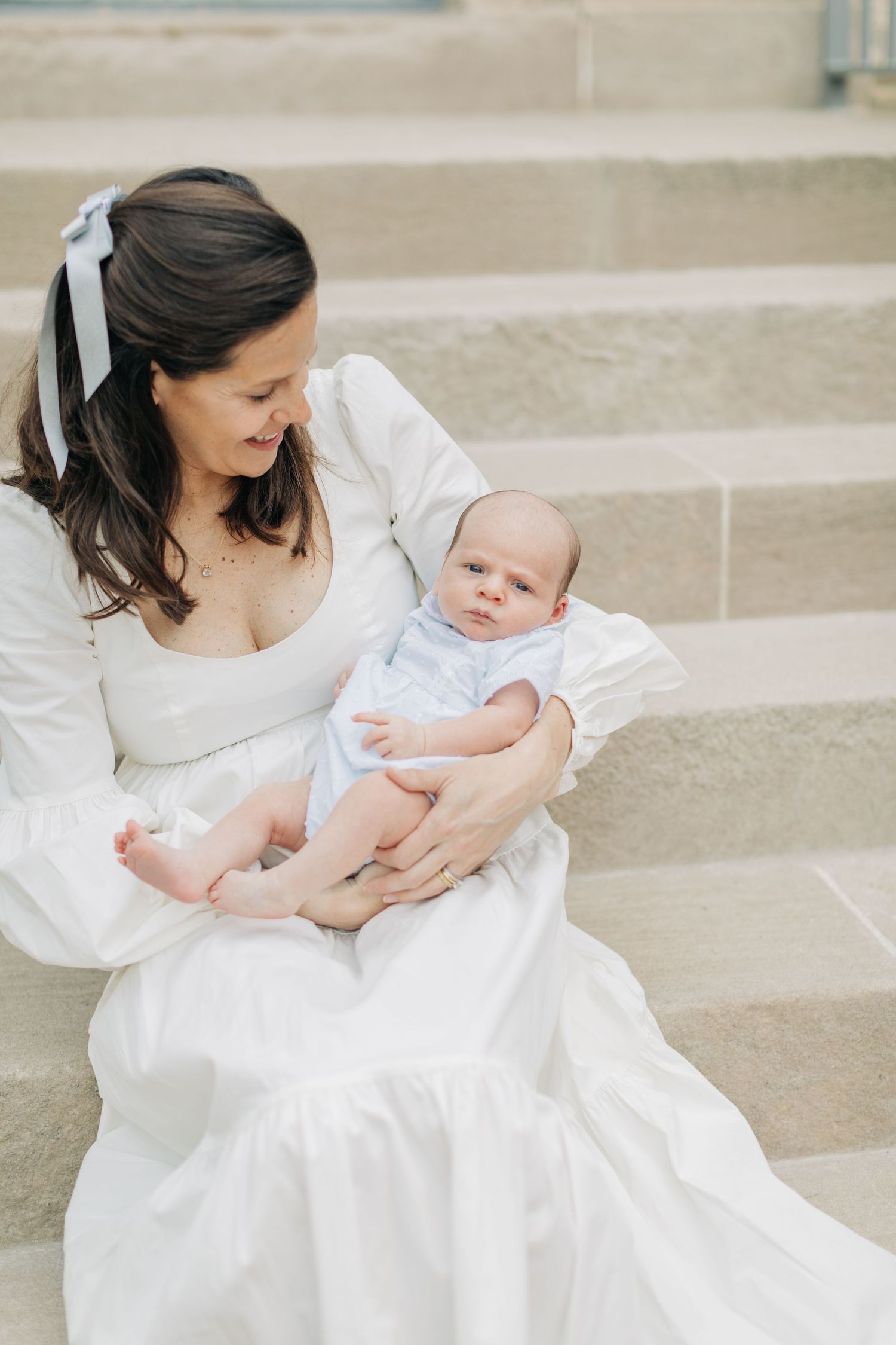 Mother and baby share intimate moment while sitting on stone steps.