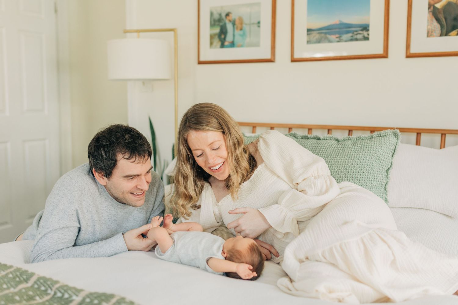 Family sharing intimate moment together on bed with framed artwork on wall.