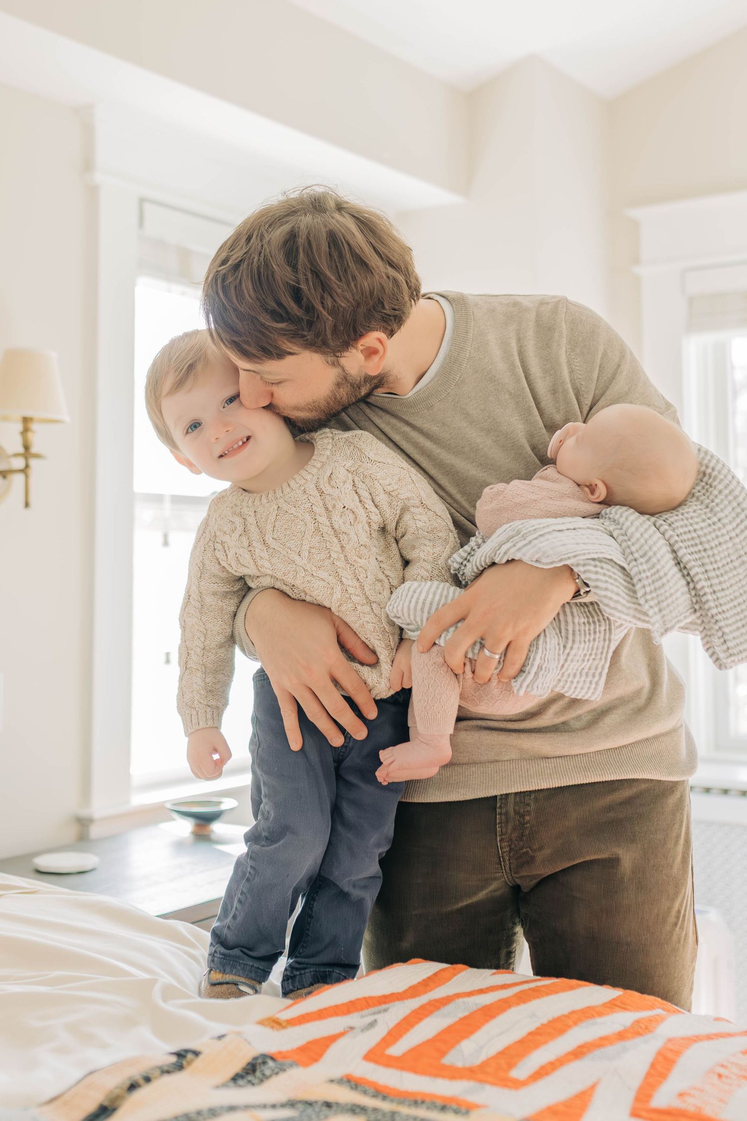 Playful family moment captured on a colorful patterned blanket in a bright room.