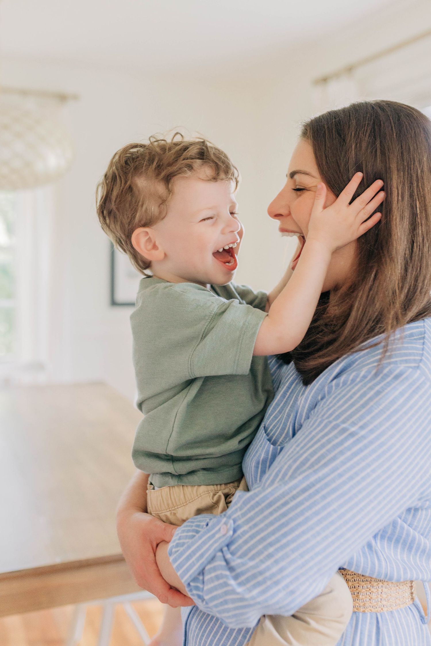Joyful embrace between parent and child in a bright white room.