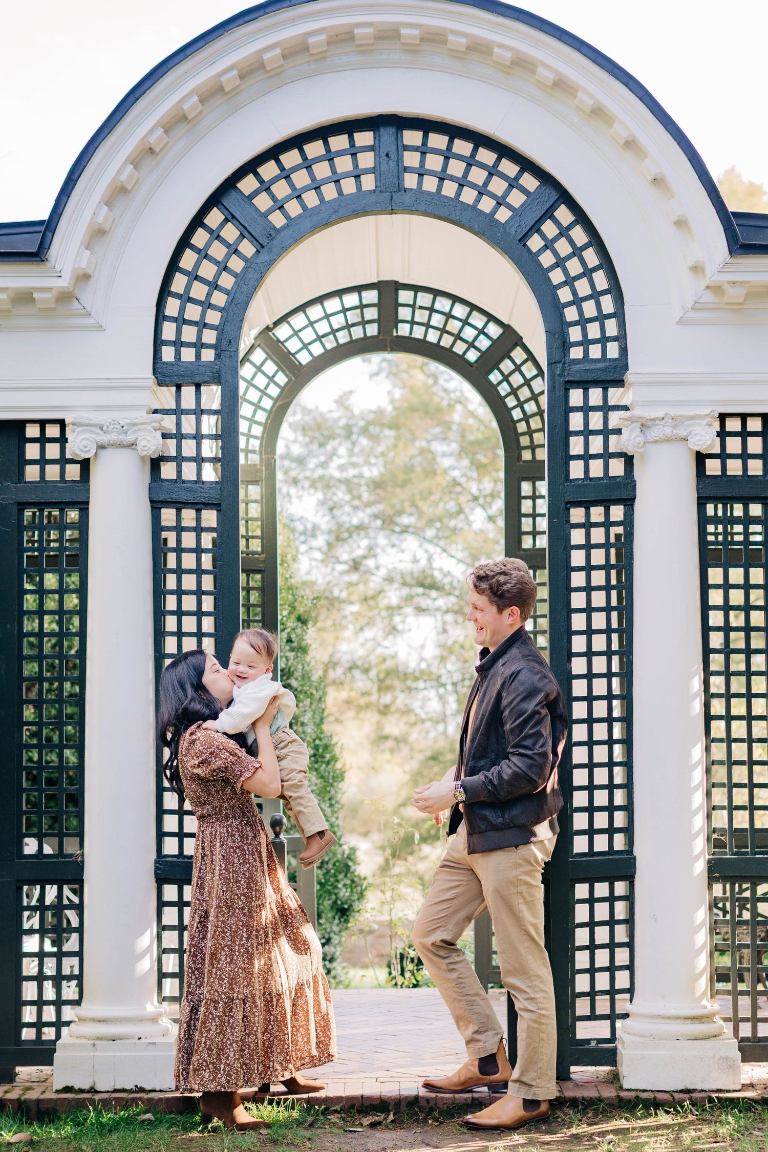 Couple posing under elegant white garden archways with lattice details during a romantic photoshoot.