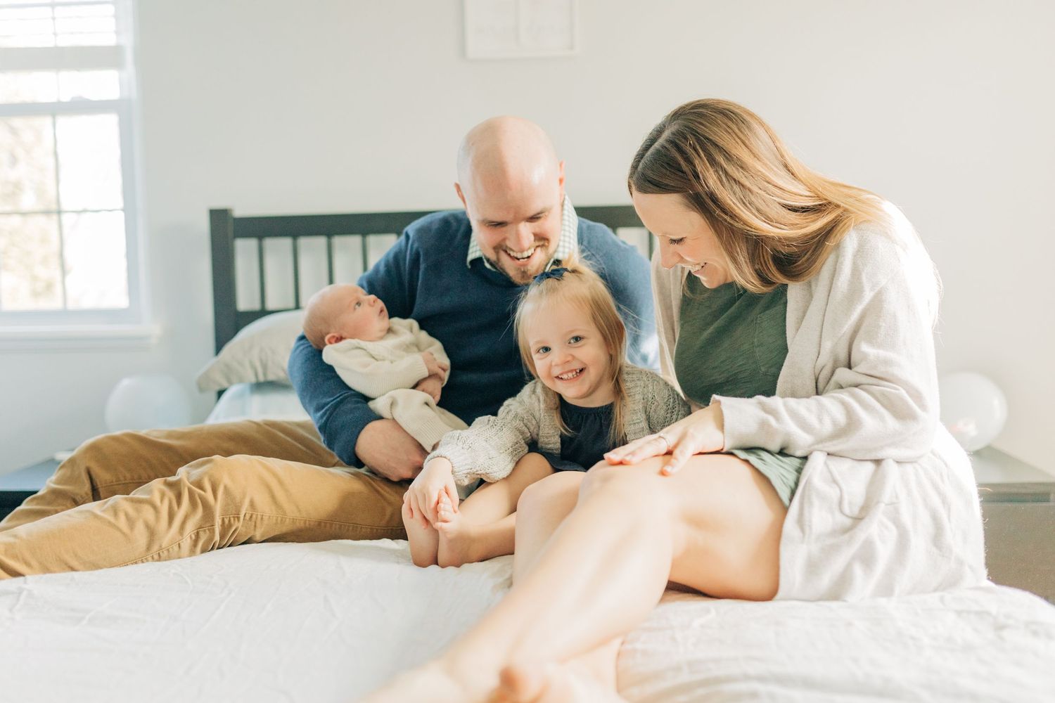 A family sharing intimate moments together while relaxing on a bed.