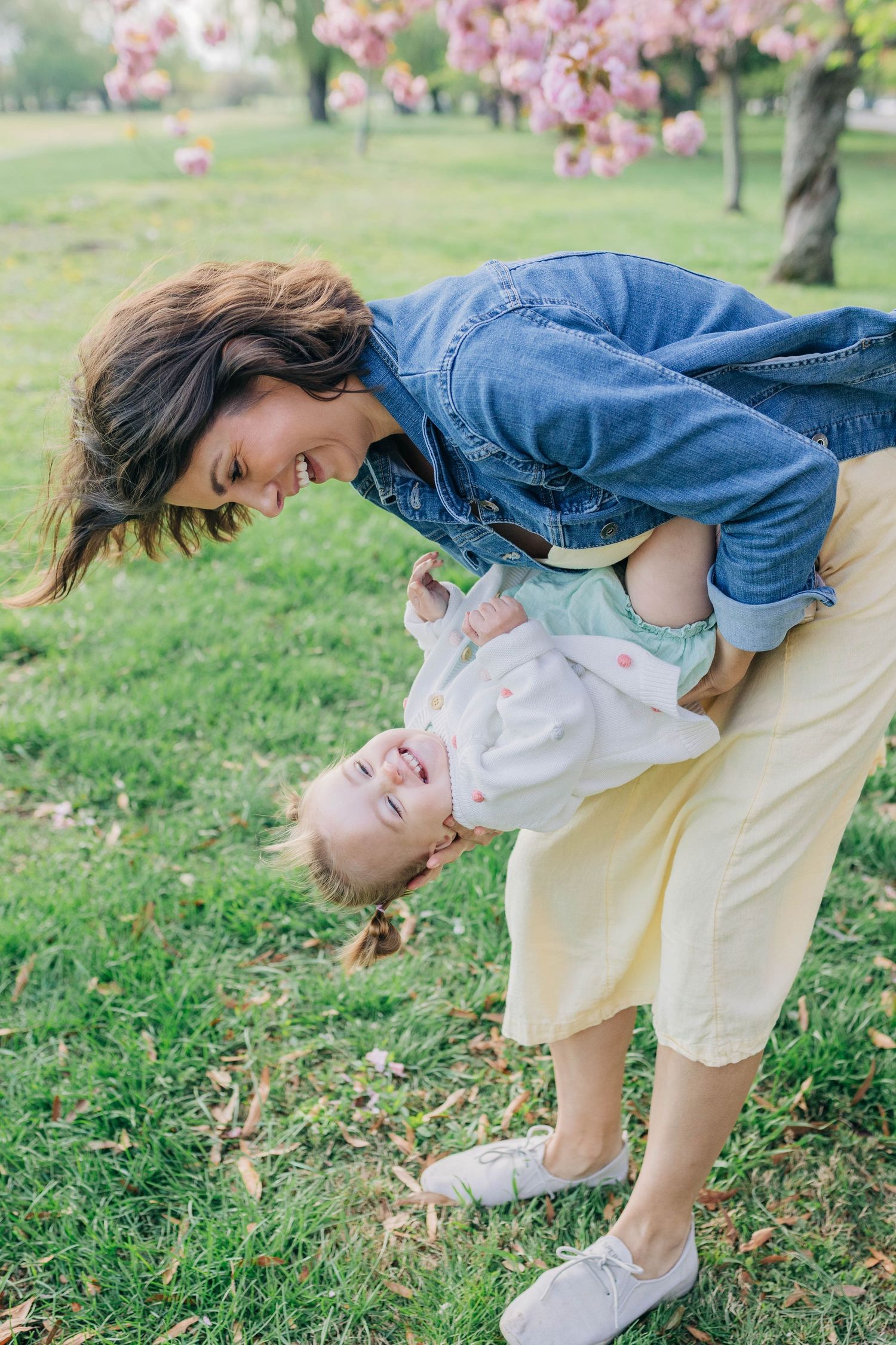 Playful moment captured in a park with blooming cherry trees and green grass.