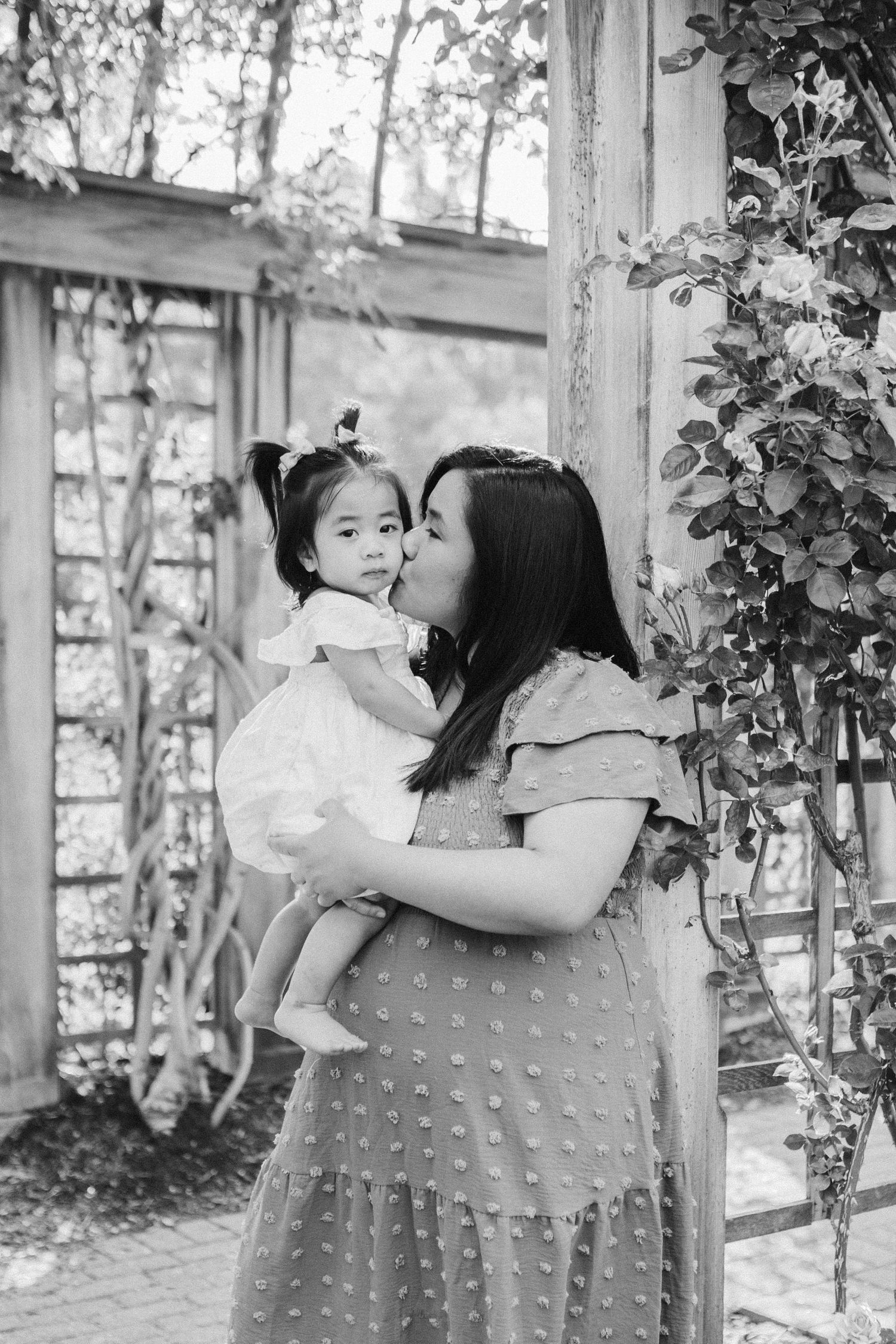 Mother and child sharing tender moments in a sunlit garden setting.