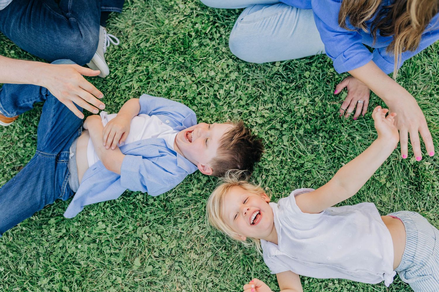 Playful family photoshoot with candid moments on green grass.