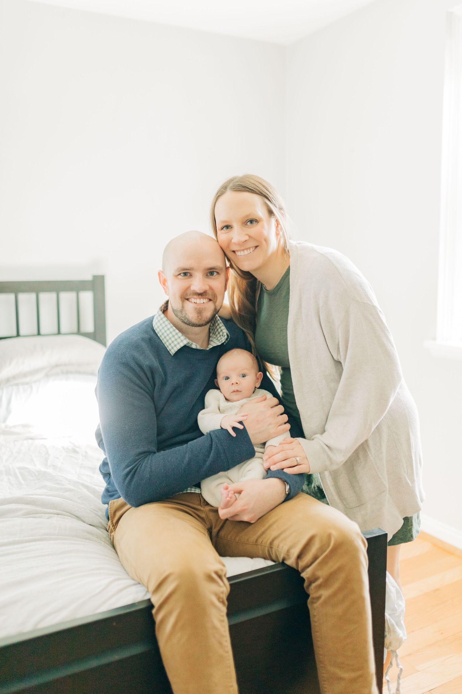 Bright lifestyle photos of family bonding with their newborn on wooden furniture.