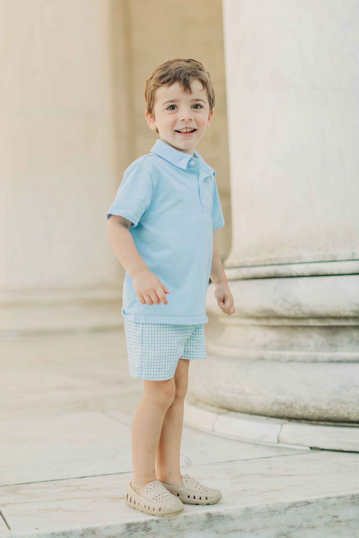 Young child in light blue outfit standing on marble steps during a photo session.