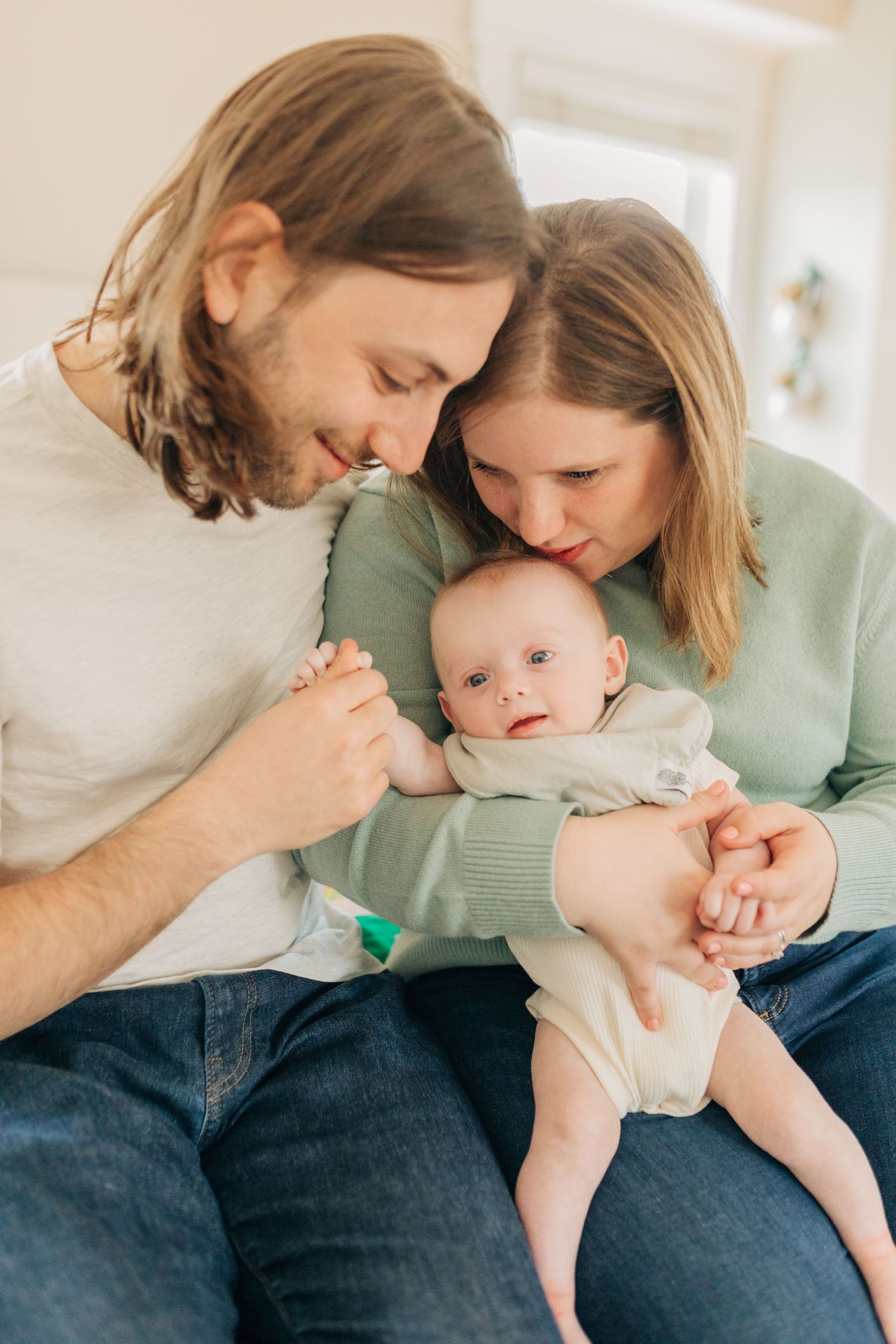Sweet candid moments of family bonding with infant on bed.