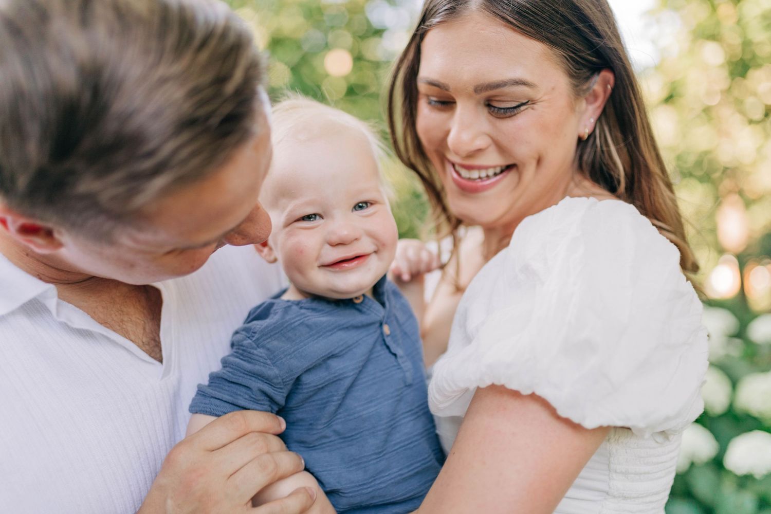 Sweet family moments photographed in a garden with white hydrangea flowers.