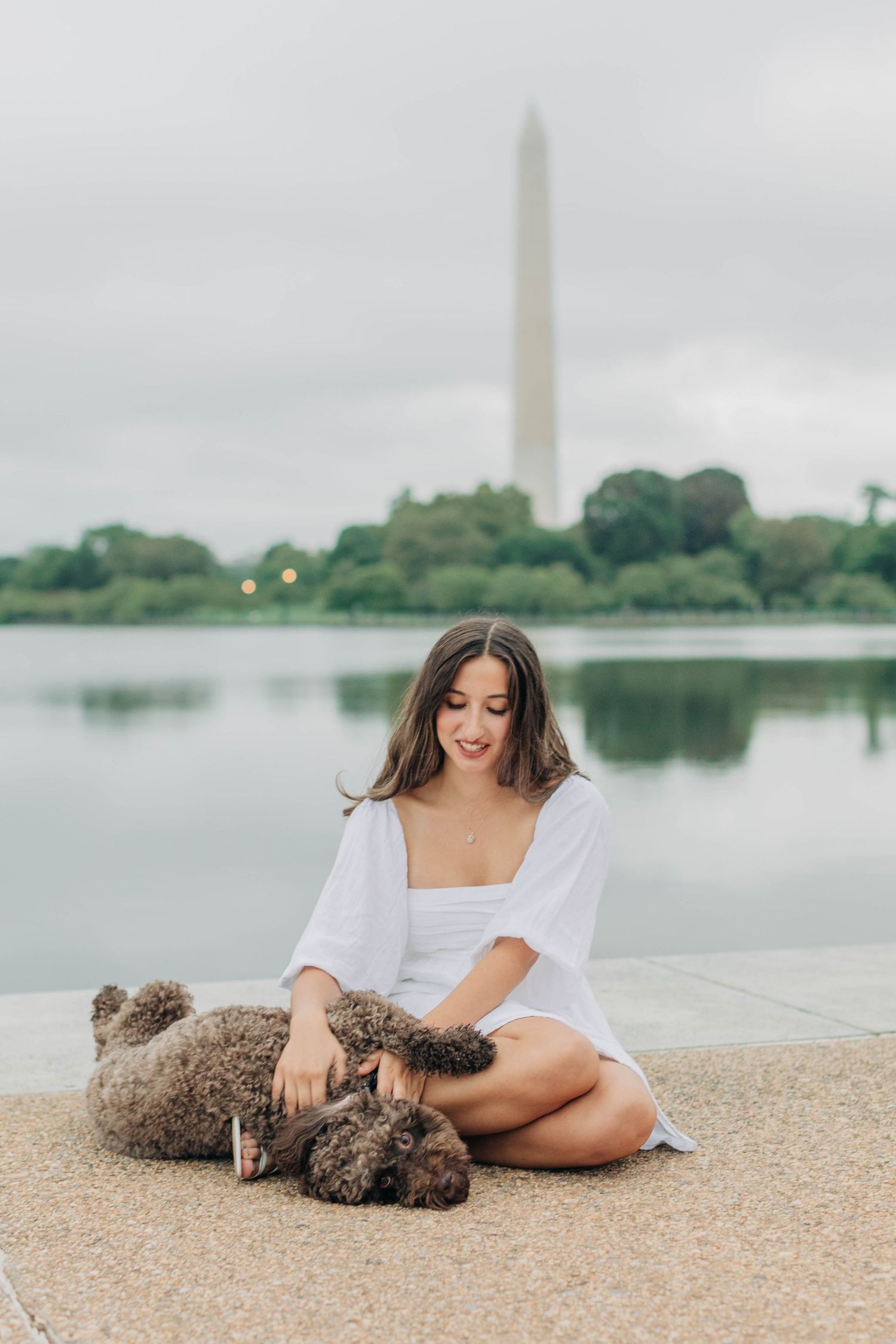 Casual poses on sandy ground with the Washington Monument visible across the water.