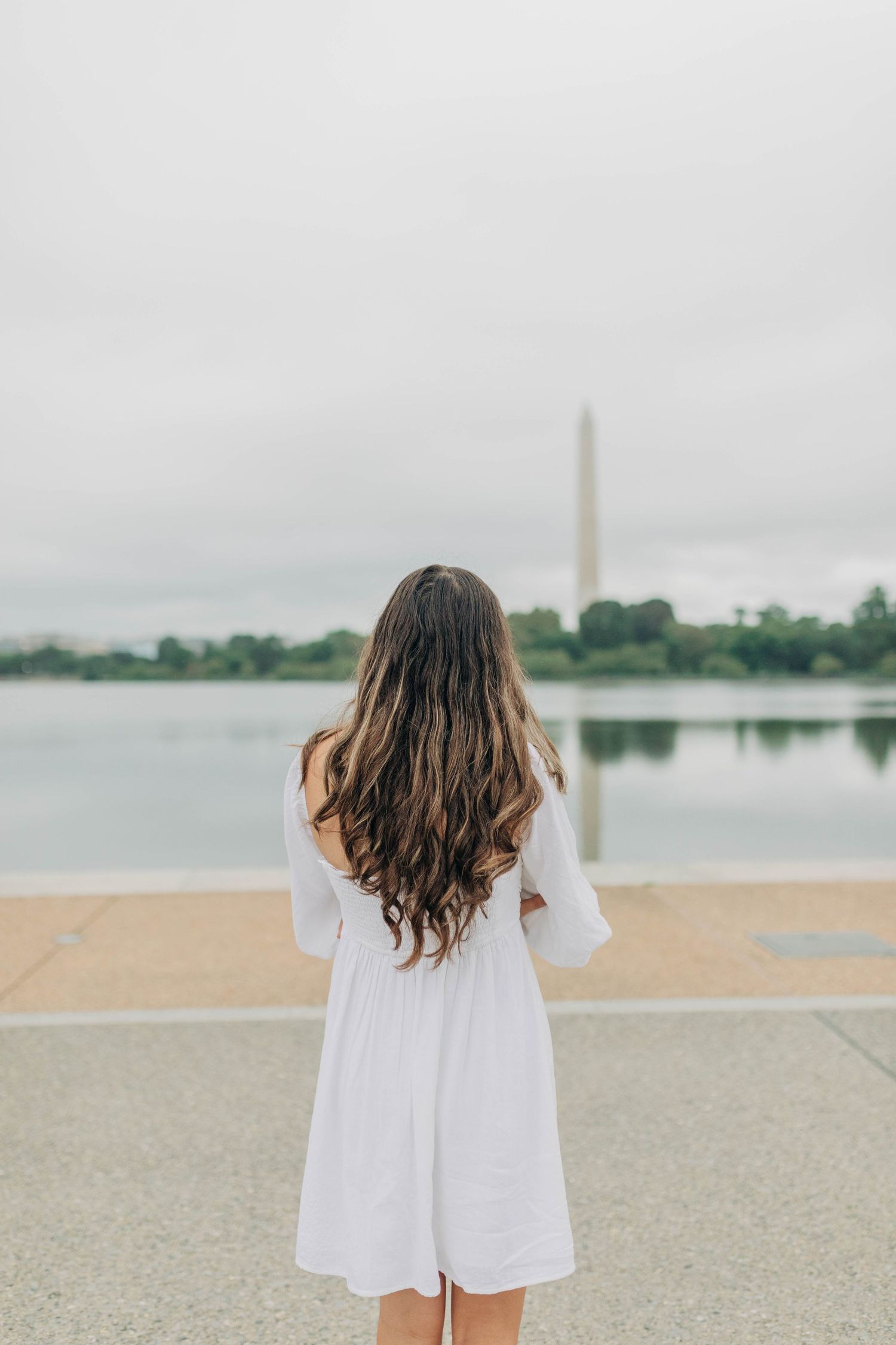 Back view of white dress against Washington Monument and reflecting pool.