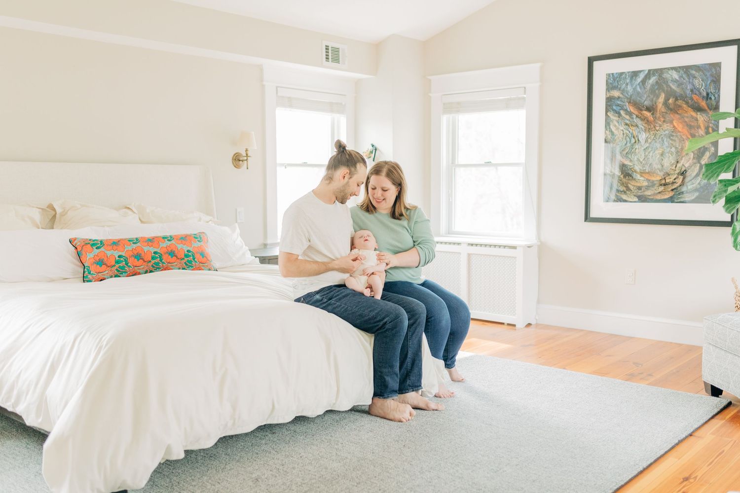 Family sharing intimate moments together in a bright, airy bedroom with white decor.